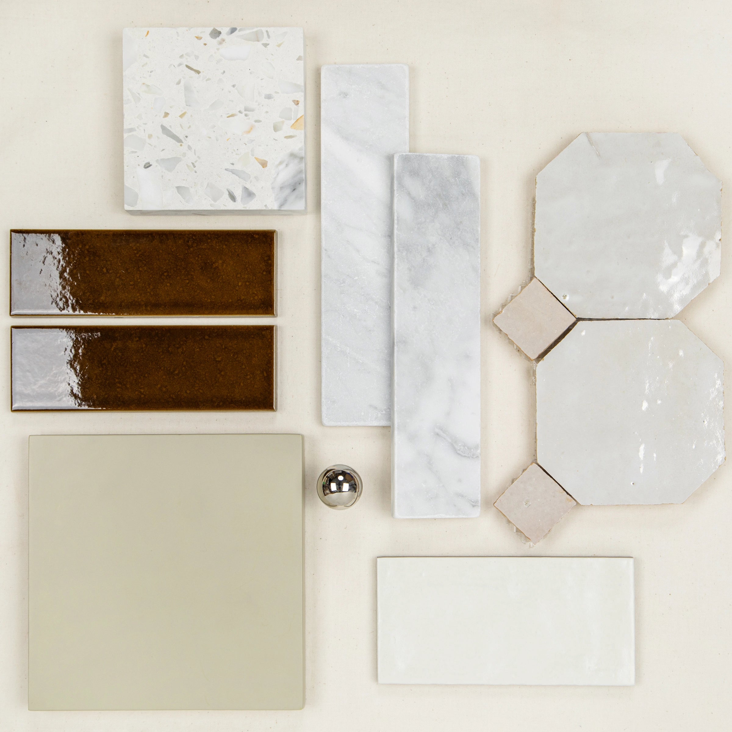 Glossy dark brown rectangular tiles paired with white marble and geometric cream porcelain tiles with a silver sphere