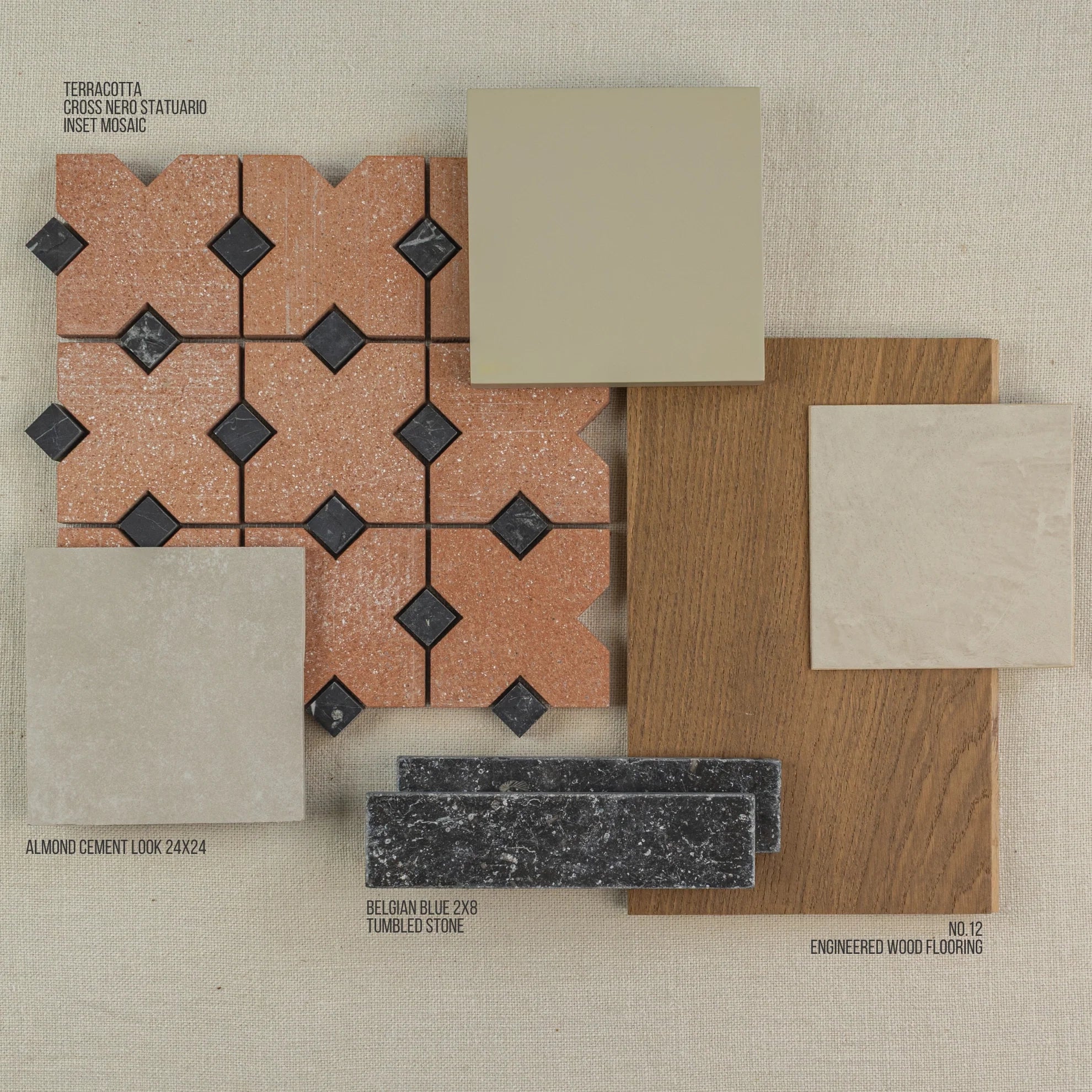 Arrangement of terracotta patterned tiles, neutral cement-look tiles, dark stone slabs, and warm oak engineered wood flooring samples on fabric