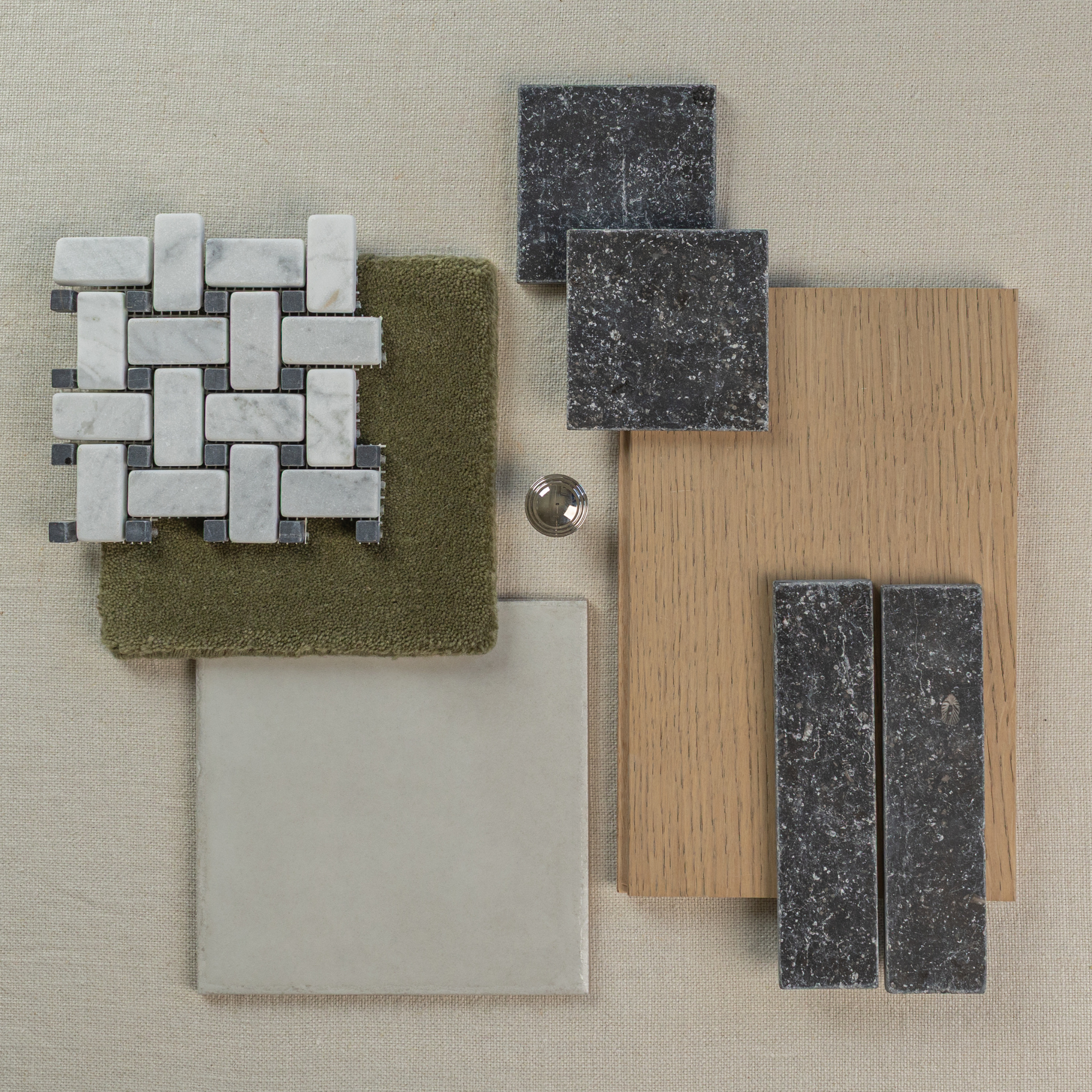 Assortment of mosaic stone tiles, textured olive fabric, wood veneer, and neutral ceramic tile on beige fabric background