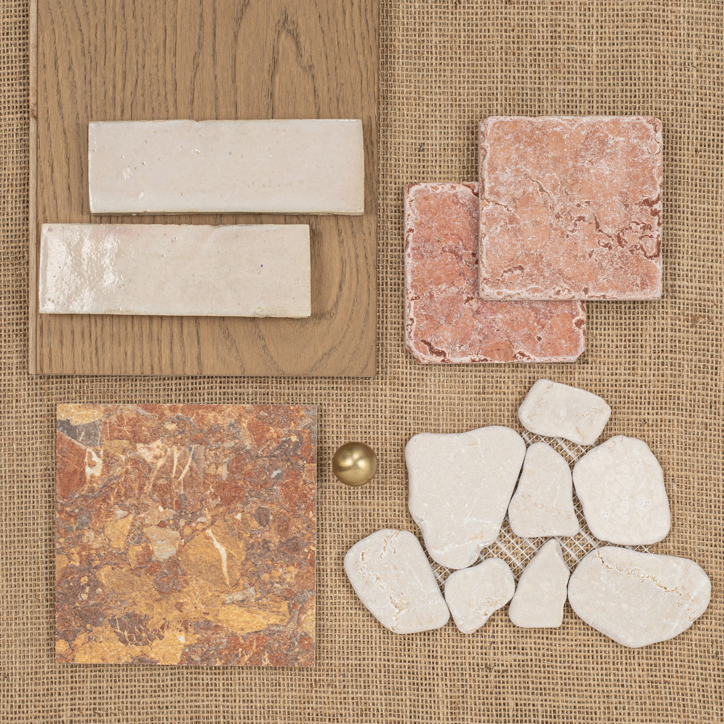 Varied natural stone and ceramic tiles with rough textures and warm tones arranged on woven fabric and wood surface