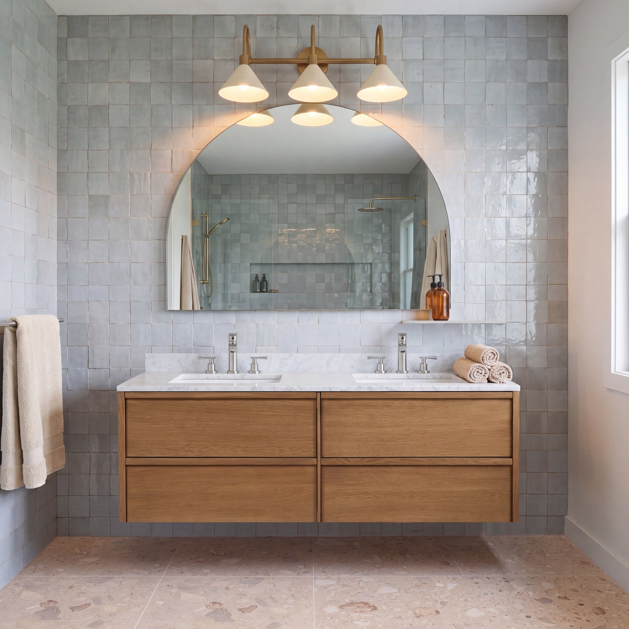 Modern bathroom with double wood vanity blue ceramic tile walls arched mirror and pendant lights