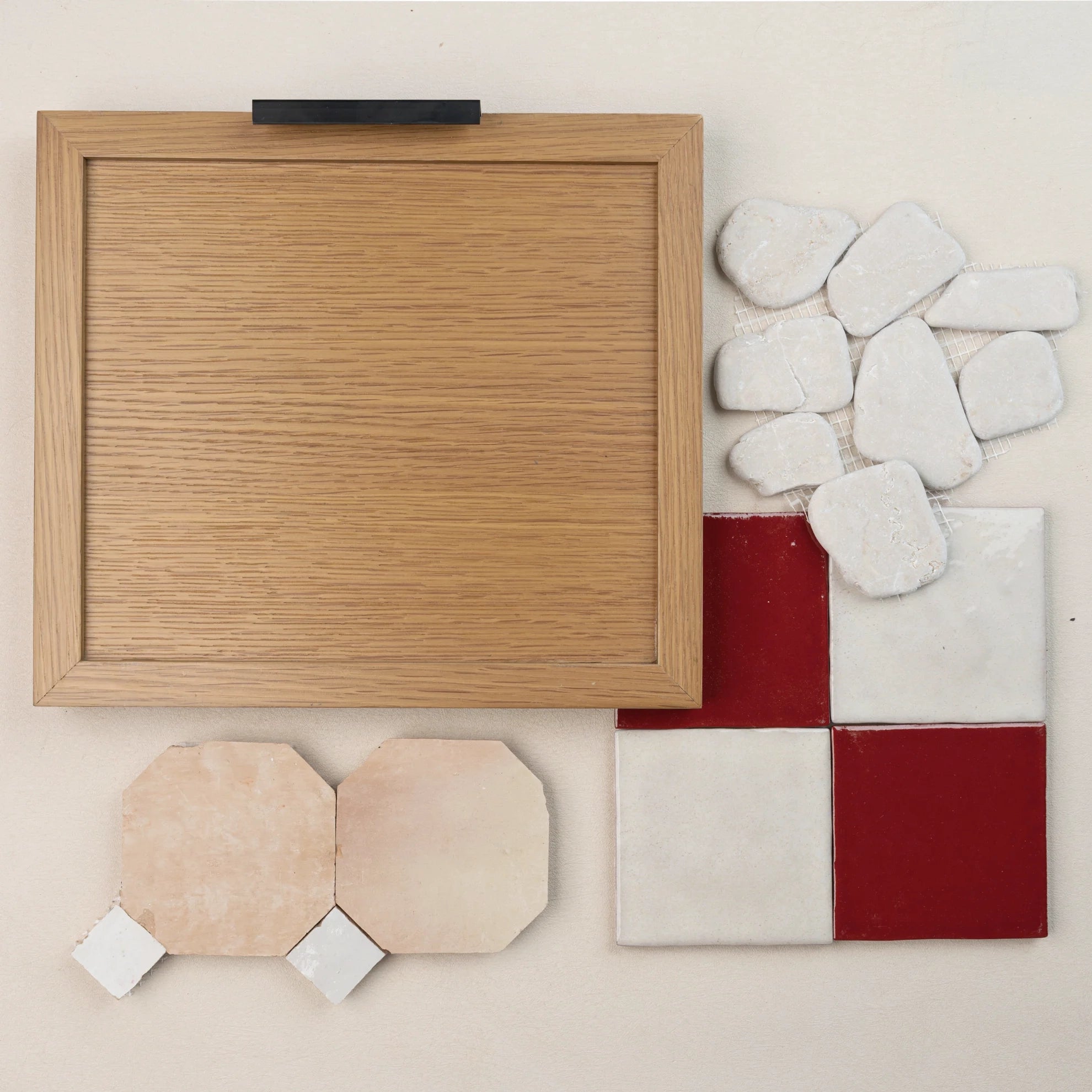 Wooden framed sample board with ceramic tiles in red and white, small stone pebbles, and beige octagonal tiles with white corners