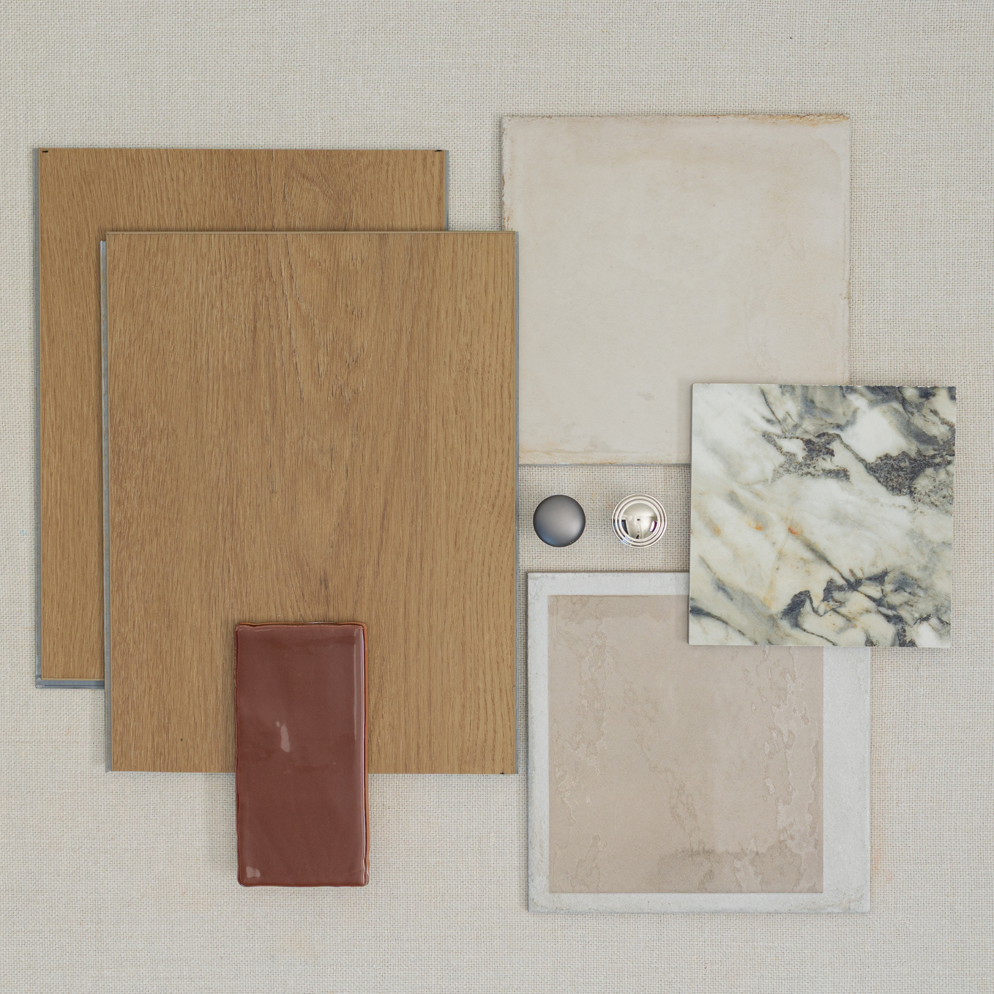 Flat lay of oak wood flooring samples, natural stone and ceramic tiles, and metallic round hardware on light fabric background