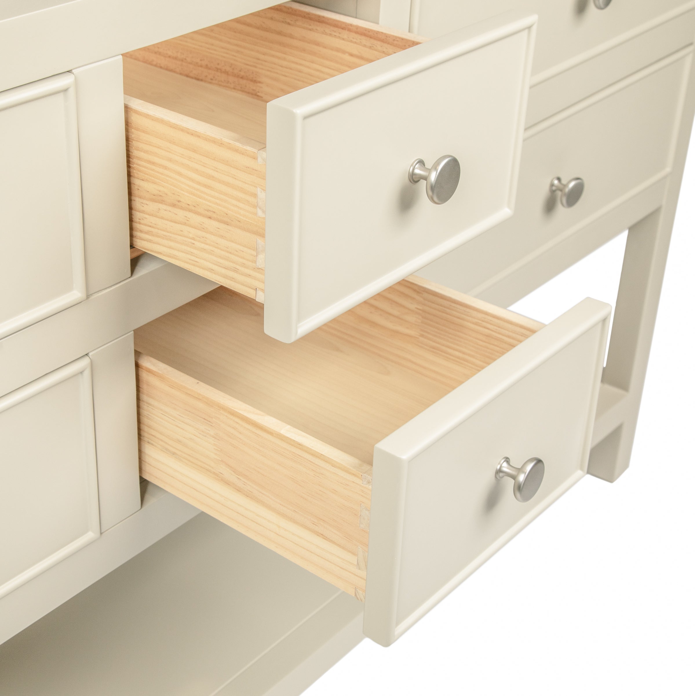 Close-up of two open cream-colored drawers with silver knobs revealing smooth natural wood interiors in a clean design