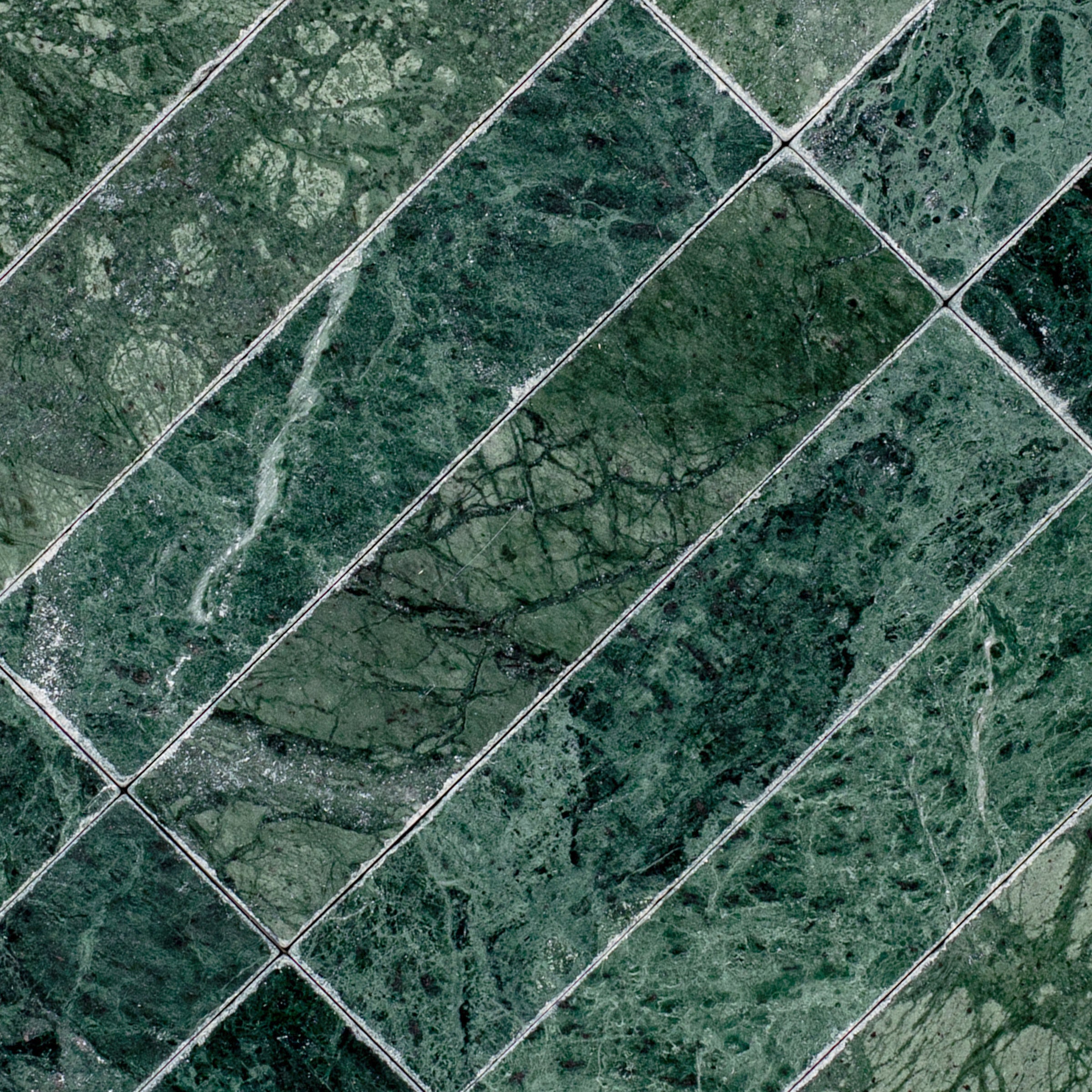Verde Guatemala 2x8 Tumbled Marble Tile in deep green with bold white veining from Tumbled Natural Stone Tiles Stone New Arrivals Best Sellers