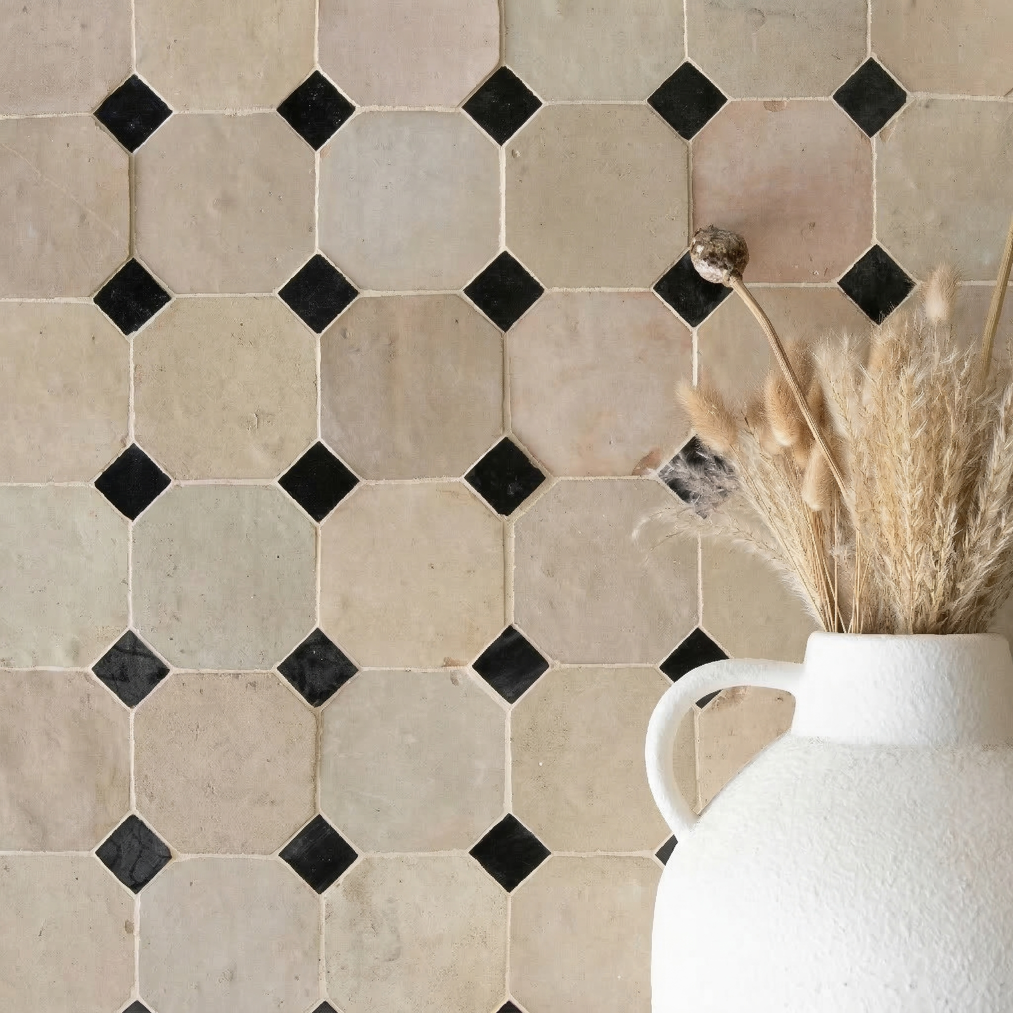 Matte beige octagonal ceramic tiles with small glossy black diamond accents beside a white vase with dried grasses
