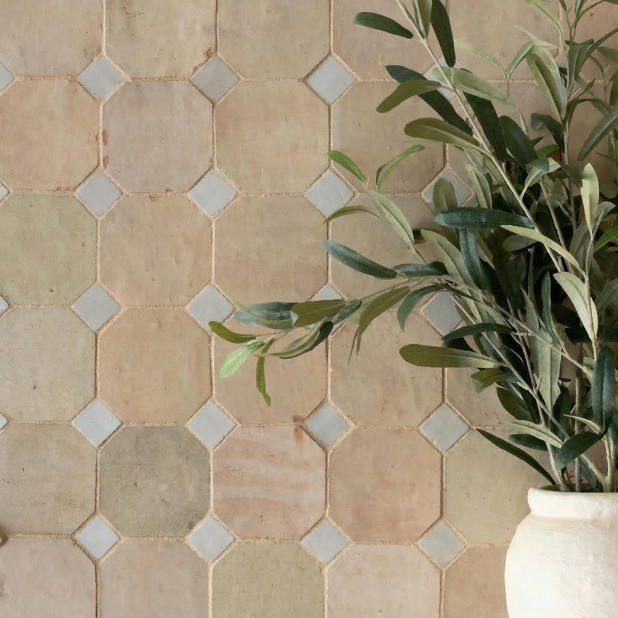Octagonal unglazed ceramic tiles in soft earth tones with small white diamond accents and greenery in a white vase nearby