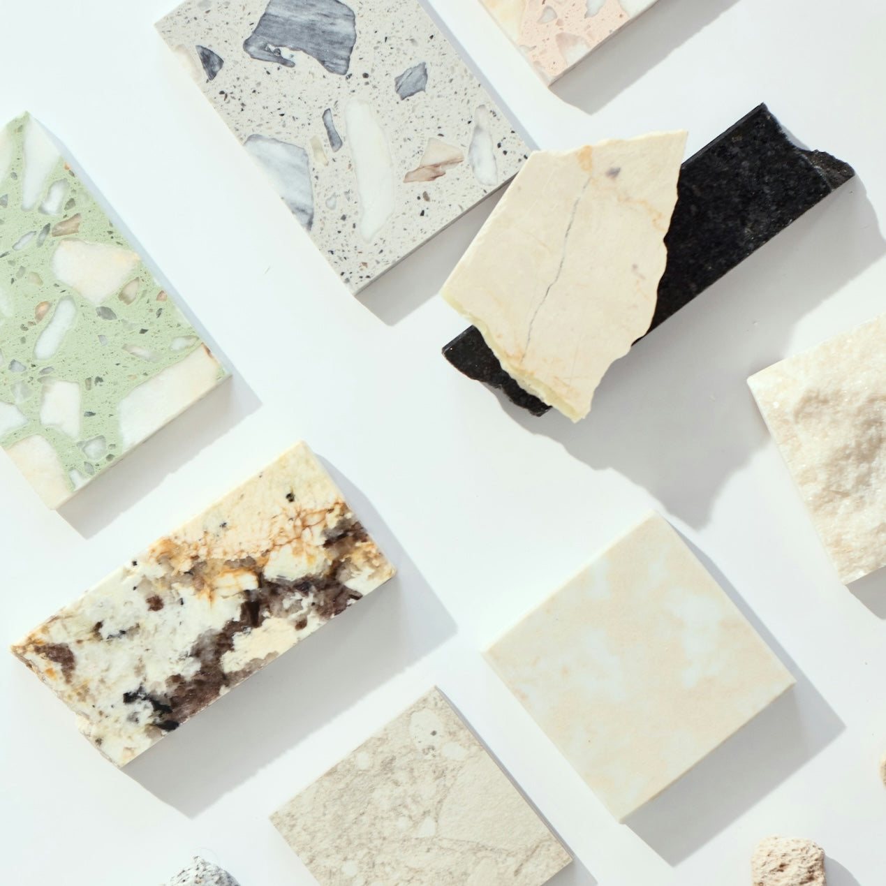 Assortment of tile and stone samples with varied natural textures and colors displayed on white surface