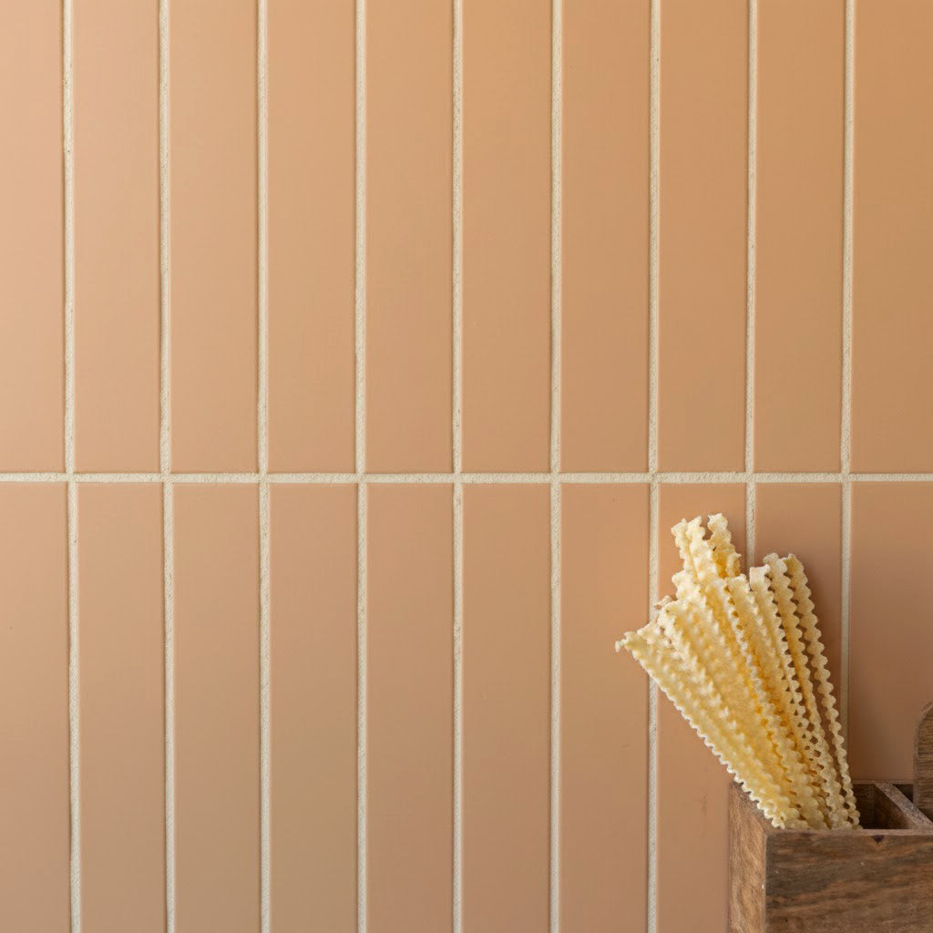 Vertical narrow matte terracotta tiles with light grout beside a wooden box holding textured pasta sticks