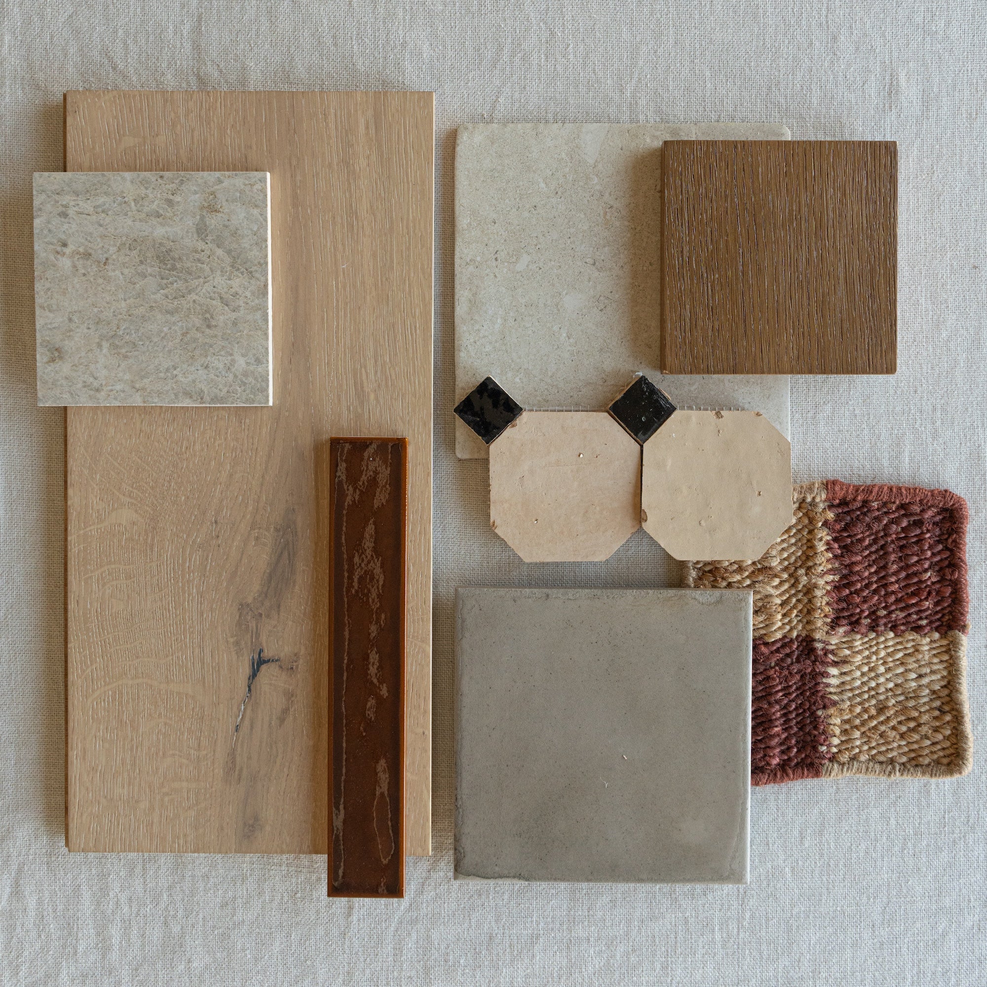 Flat lay of light and medium wood samples, beige stone tiles, gray ceramic tile, and textured woven fabric swatch