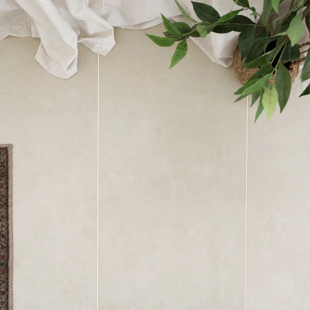 Large format beige tiles with a leafy plant white fabric and rug edge