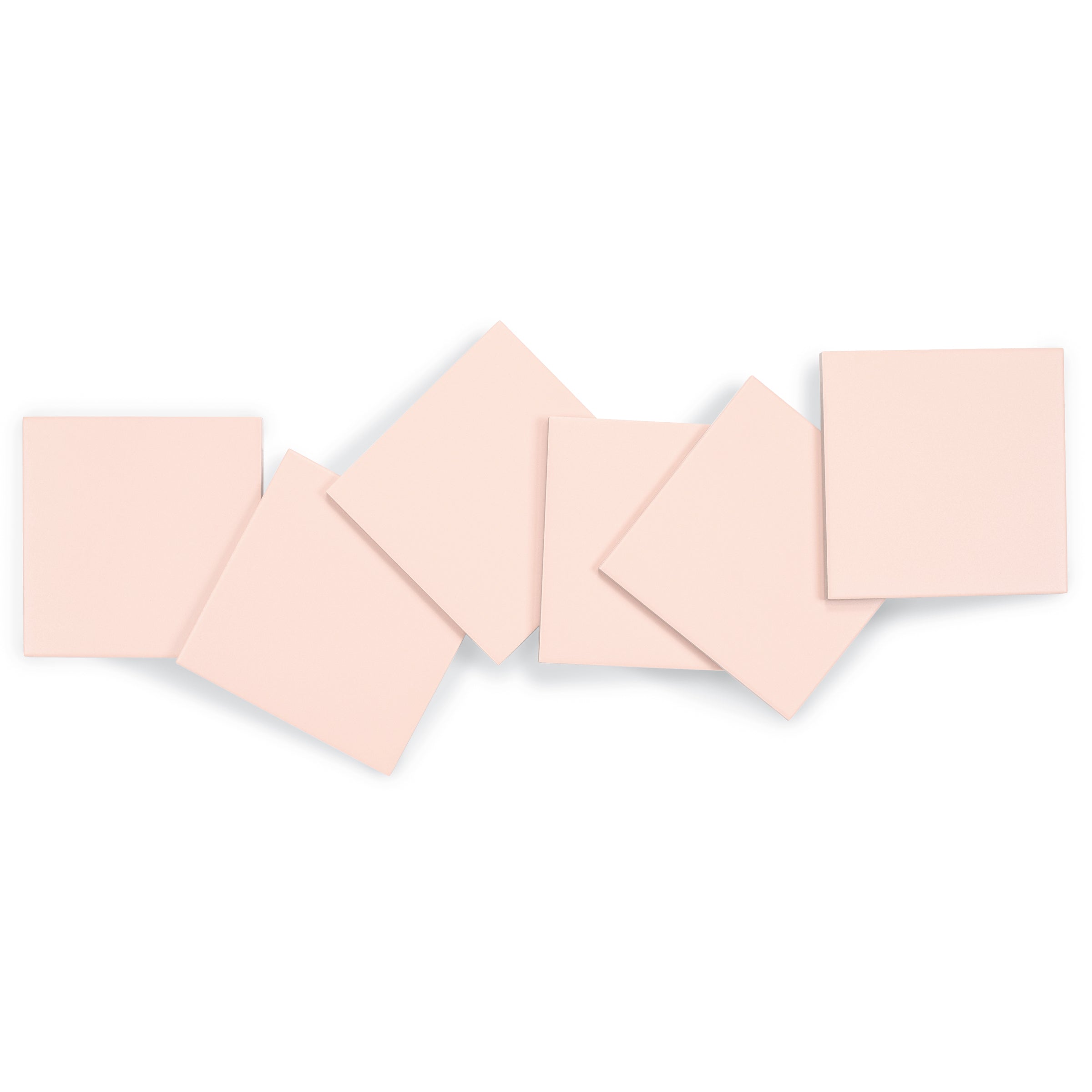 Light blush-colored porcelain tiles with a smooth matte finish and clean edges arranged casually on white background