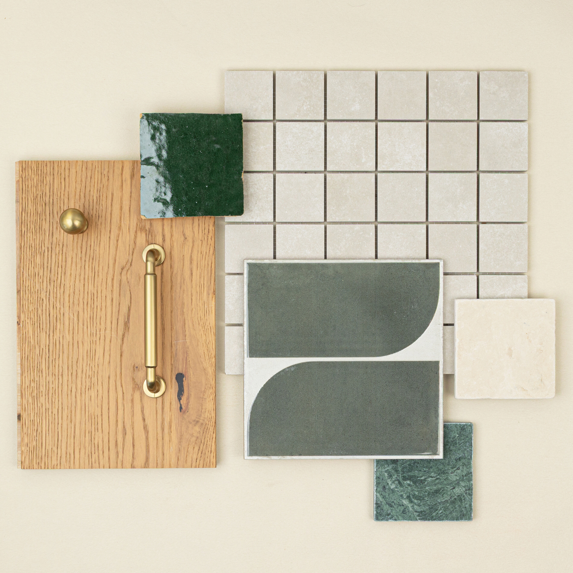 Flat lay of oak wood sample with brass knob and handle, green glazed and matte ceramic tiles, and light beige square mosaic tiles