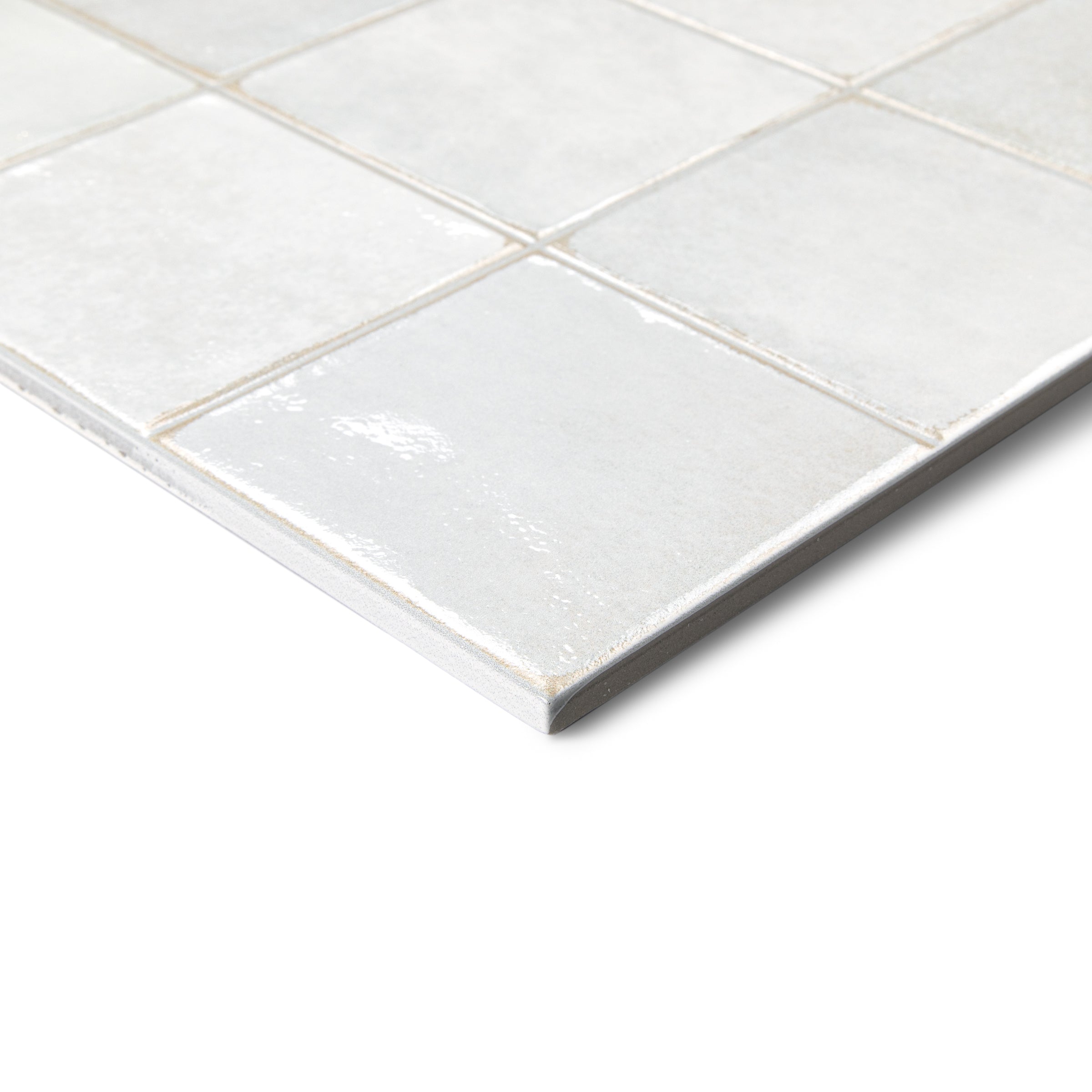 Glossy white ceramic tiles with subtle texture and grout lines on a flat surface at an angle.