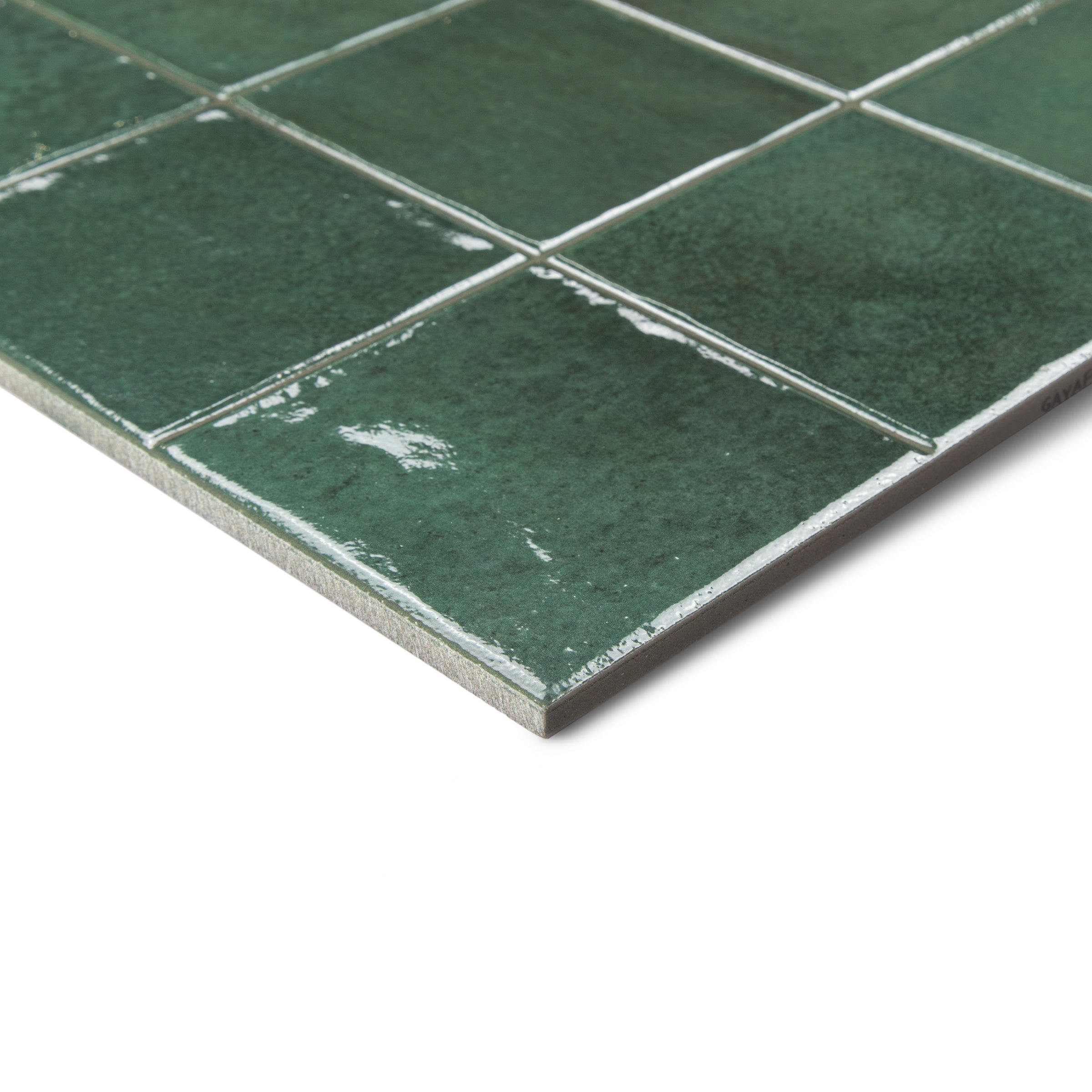 Close-up of green ceramic tiles with glossy finish and visible grout lines on white background