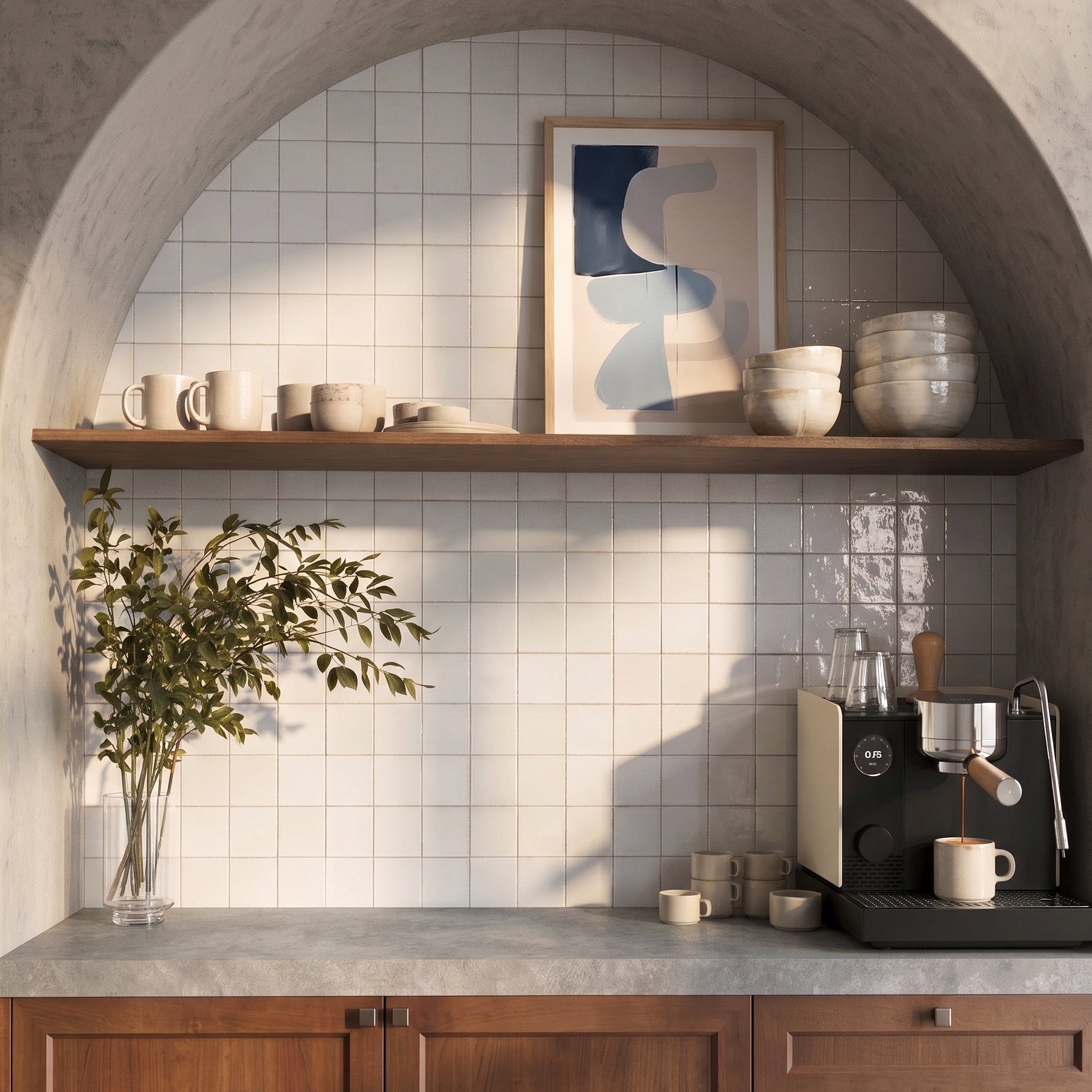 Minimalist kitchen corner with white square tiles, wooden shelf, modern art, ceramics, and espresso machine with cups