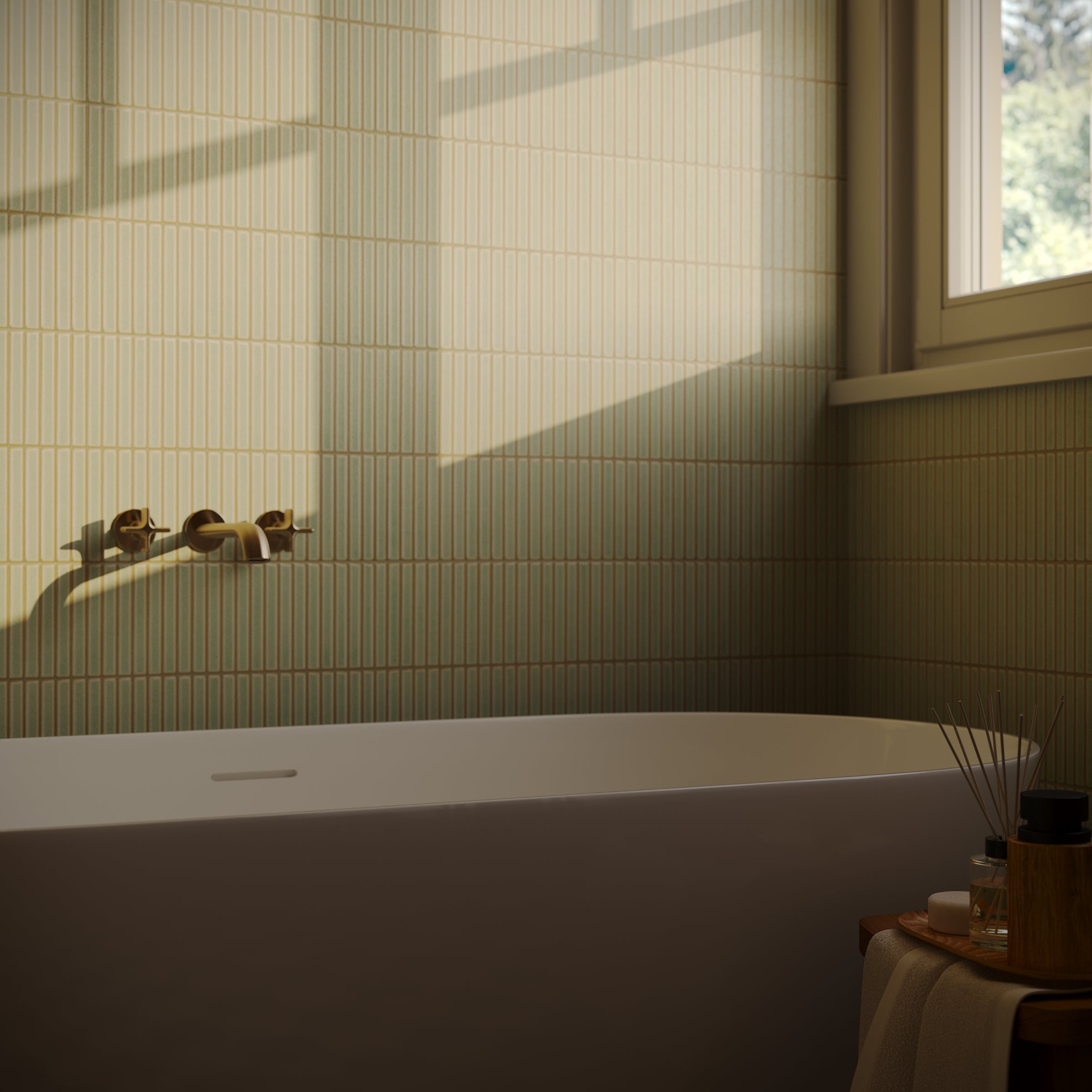 Sunlit bathroom corner with a modern bathtub, small format ceramic tiles, brass fixtures, and a window view.