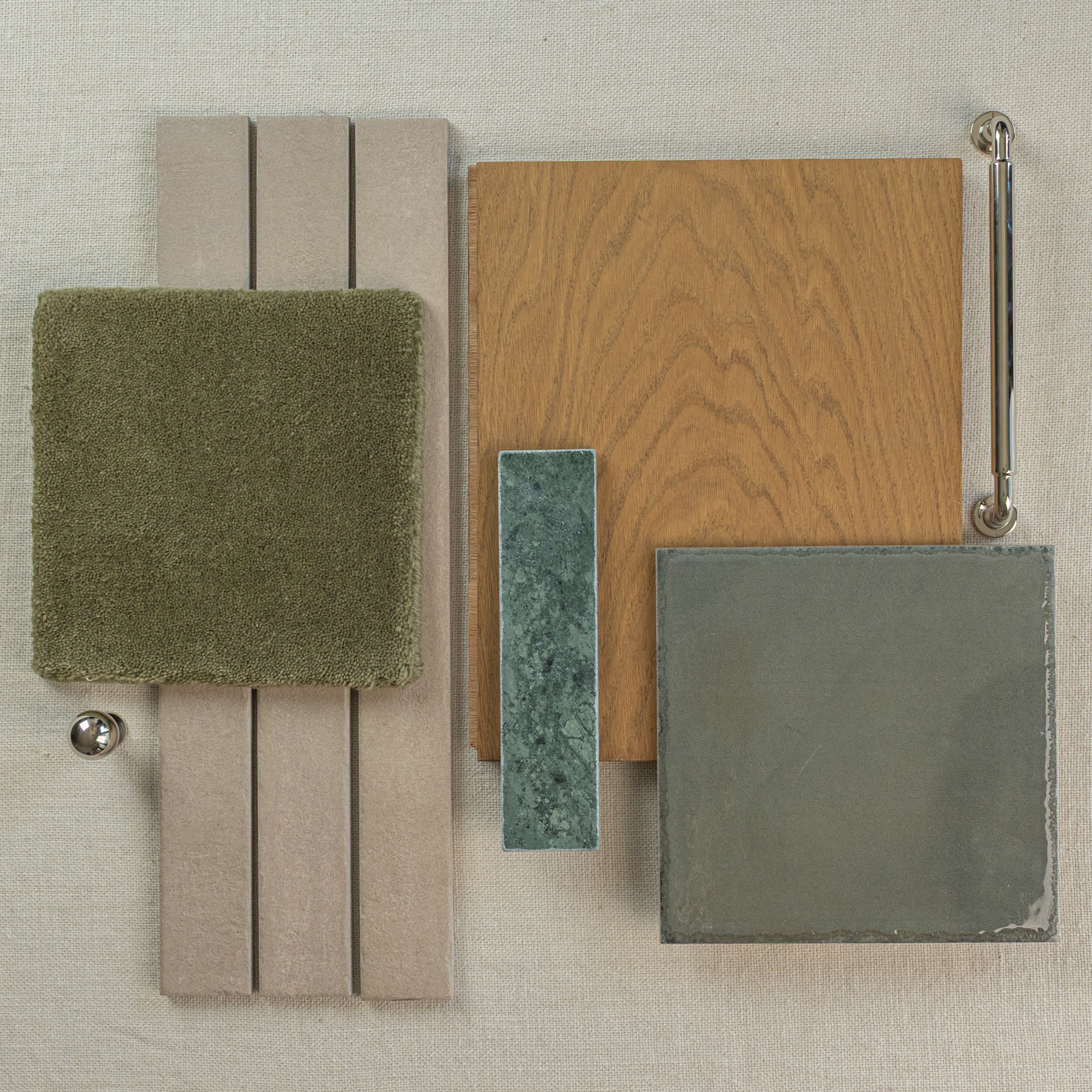 Flat lay of flooring and tile samples in natural wood, muted green stone, mossy fabric, and soft beige tones with a metal handle and knob