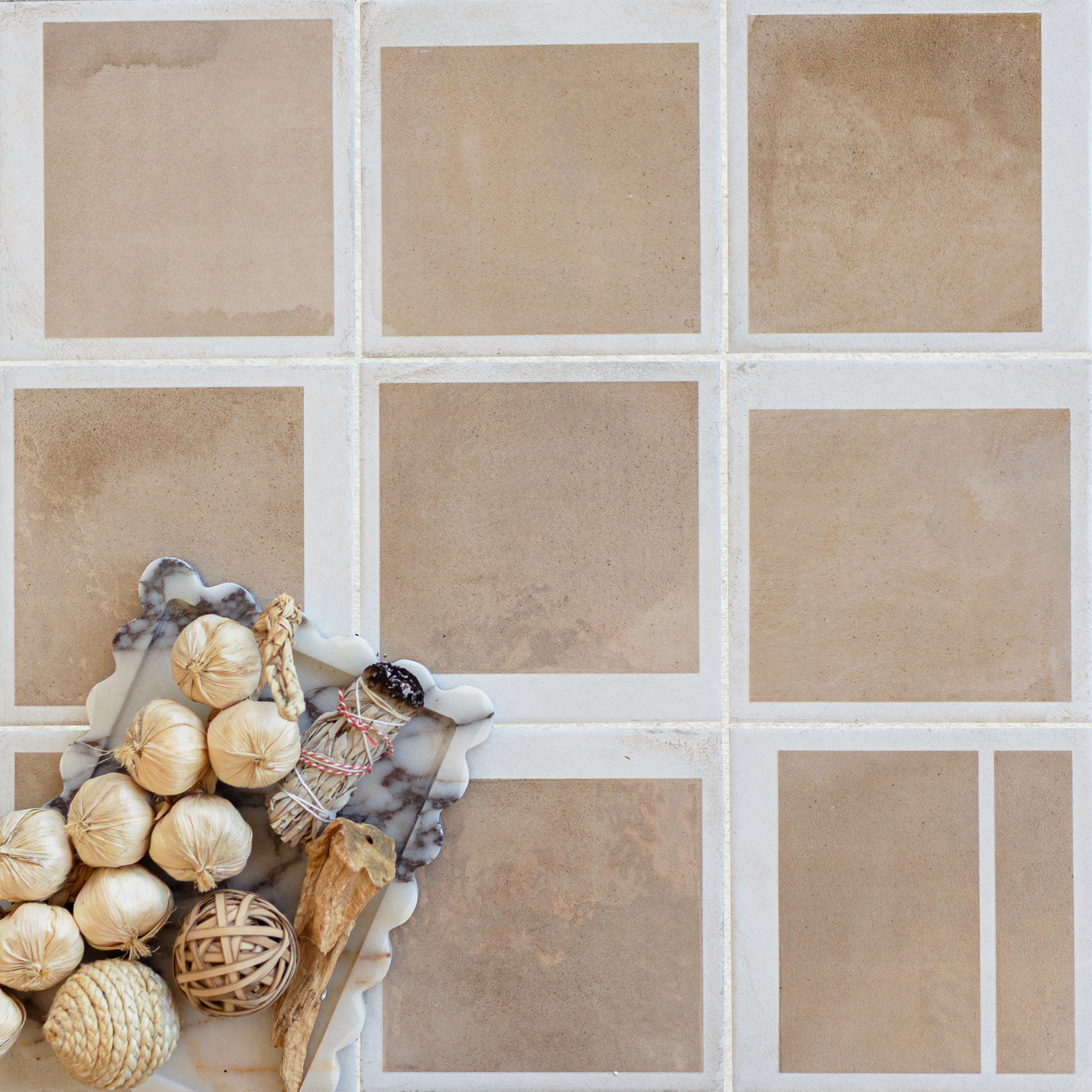 Warm terracotta square tiles with a marble tray holding dried botanicals and natural woven decorative balls