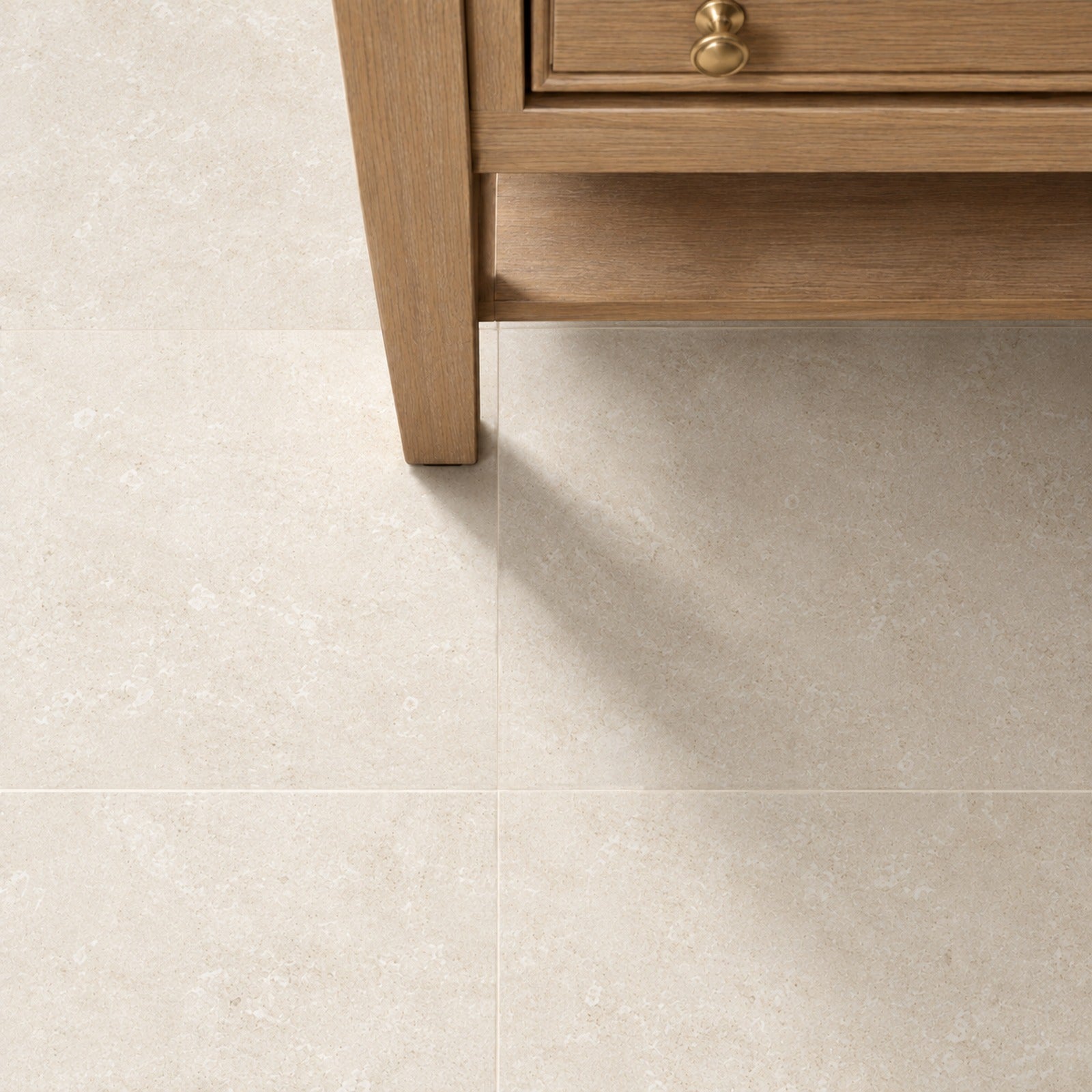 Wood cabinet with brass pulls above large beige tiled flooring