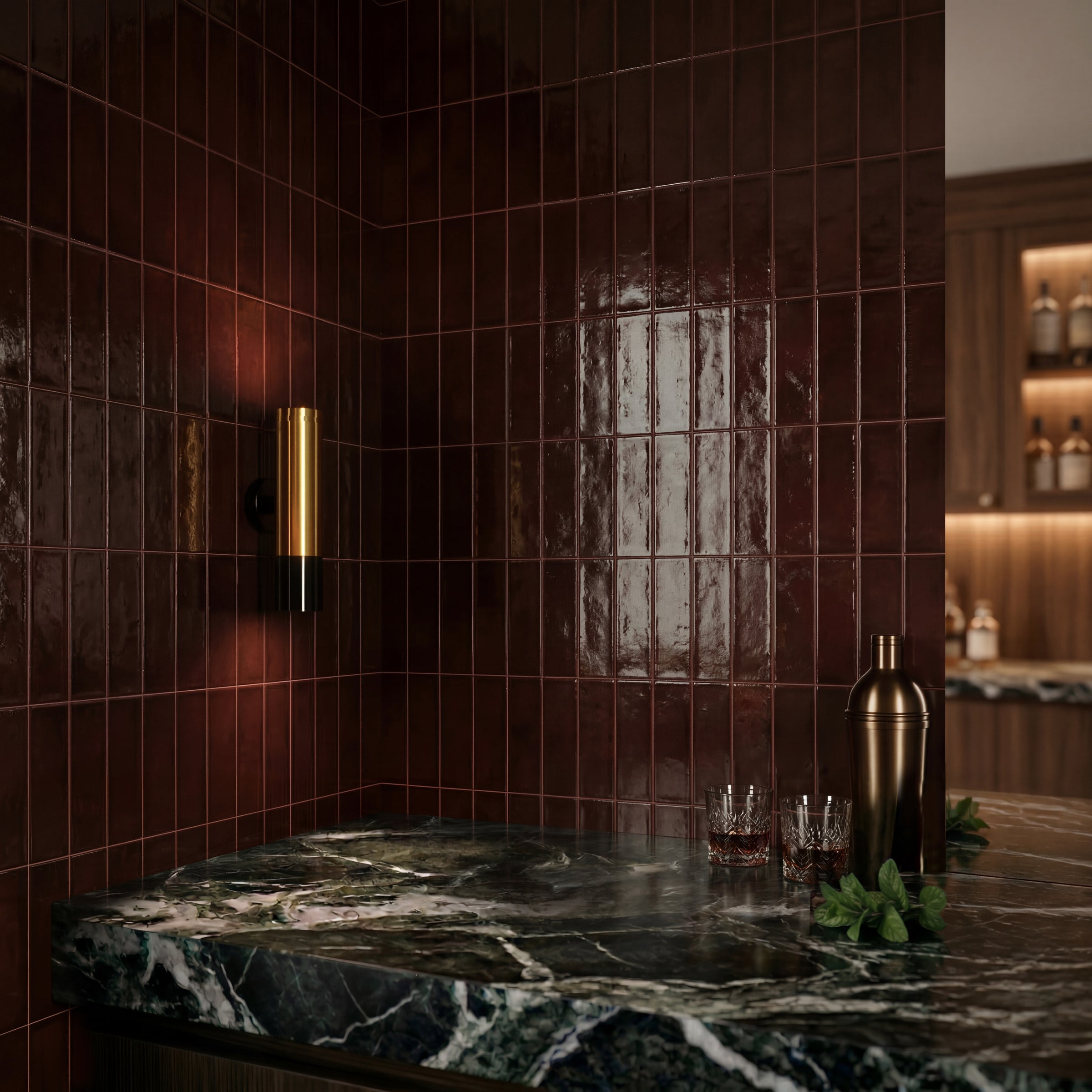 Dark mahogany ceramic tile wall with glossy finish next to a black and green marble countertop with brass light fixture