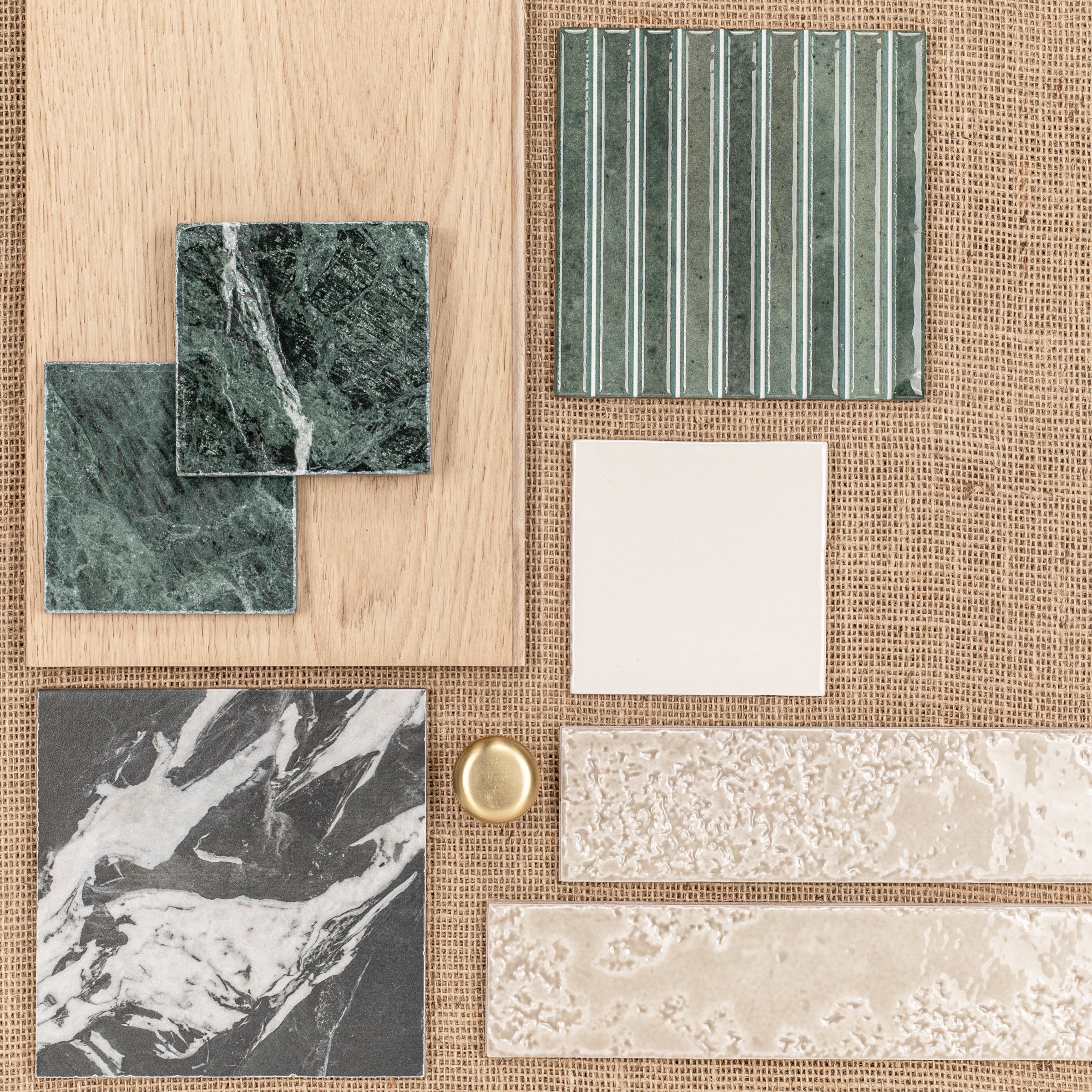Green marble and textured green ceramic tiles paired with light wood and neutral beige tiles on woven fabric background