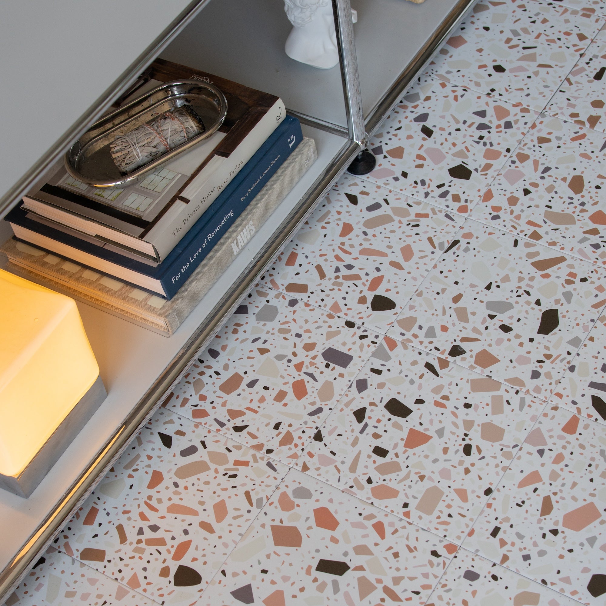 Terrazzo flooring with multicolored stone chips next to a metal bookshelf holding books and a tray