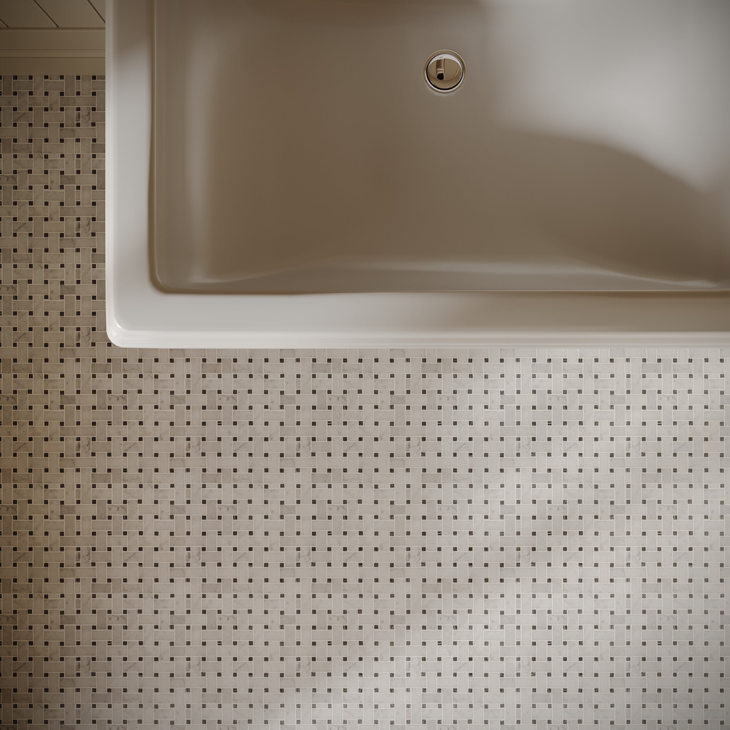 Top-down view of light beige mosaic tile floor with small dark square accents next to a matte white bathtub edge.
