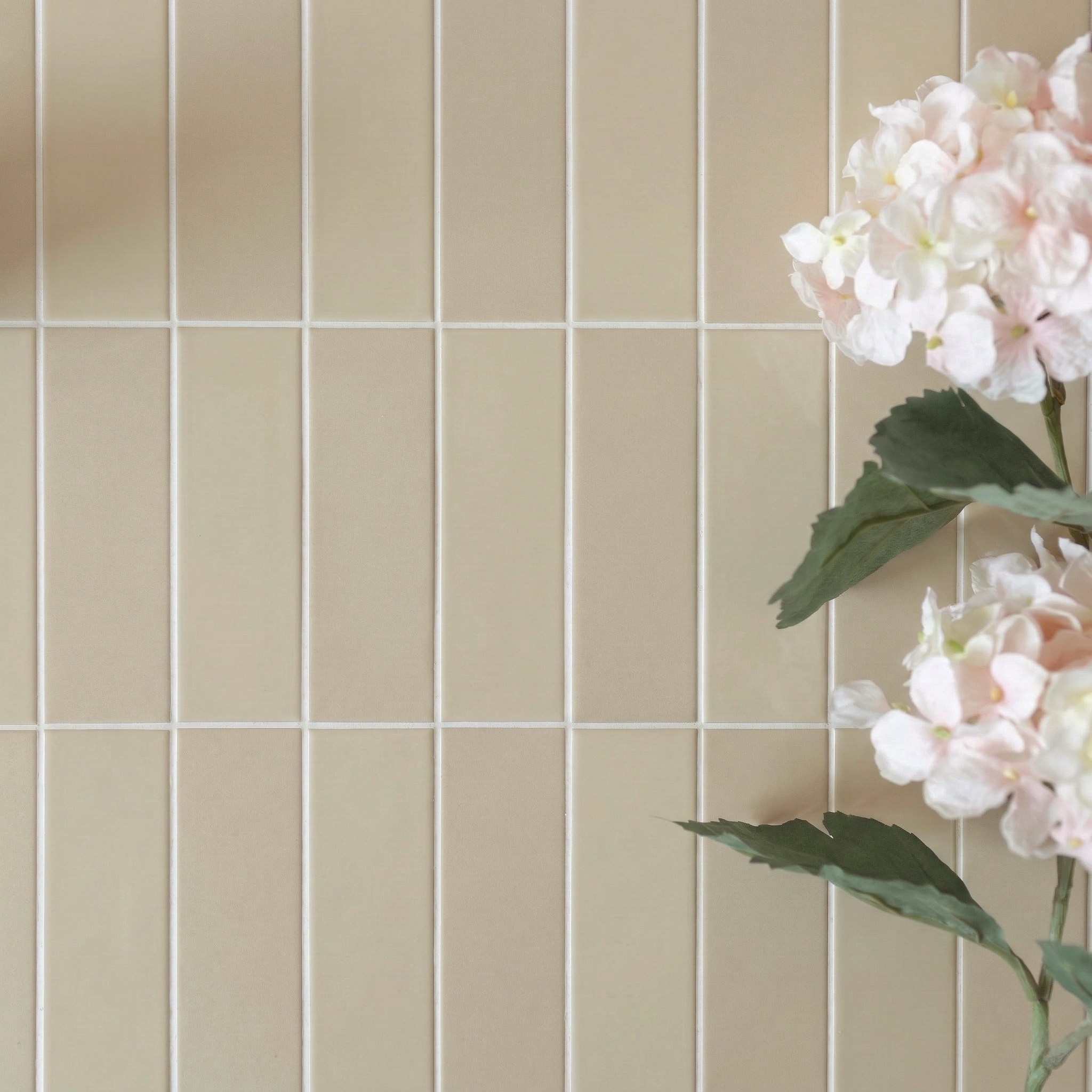 Beige vertical rectangular porcelain tiles wall with soft pink hydrangea flowers on the right side, elegant design setting