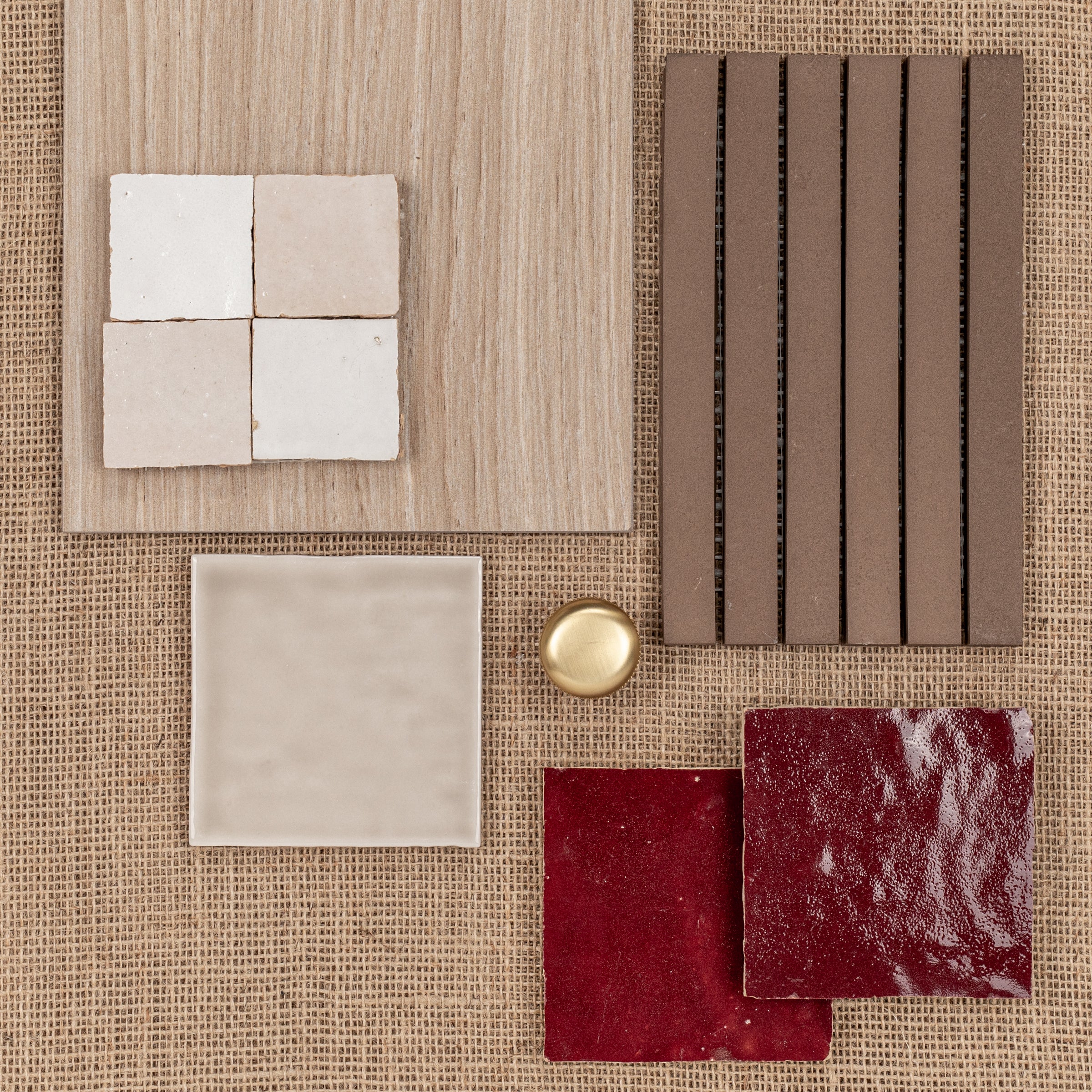 Natural beige wood plank with textured ceramic tiles and deep red and brown glazed tile samples on woven fabric background