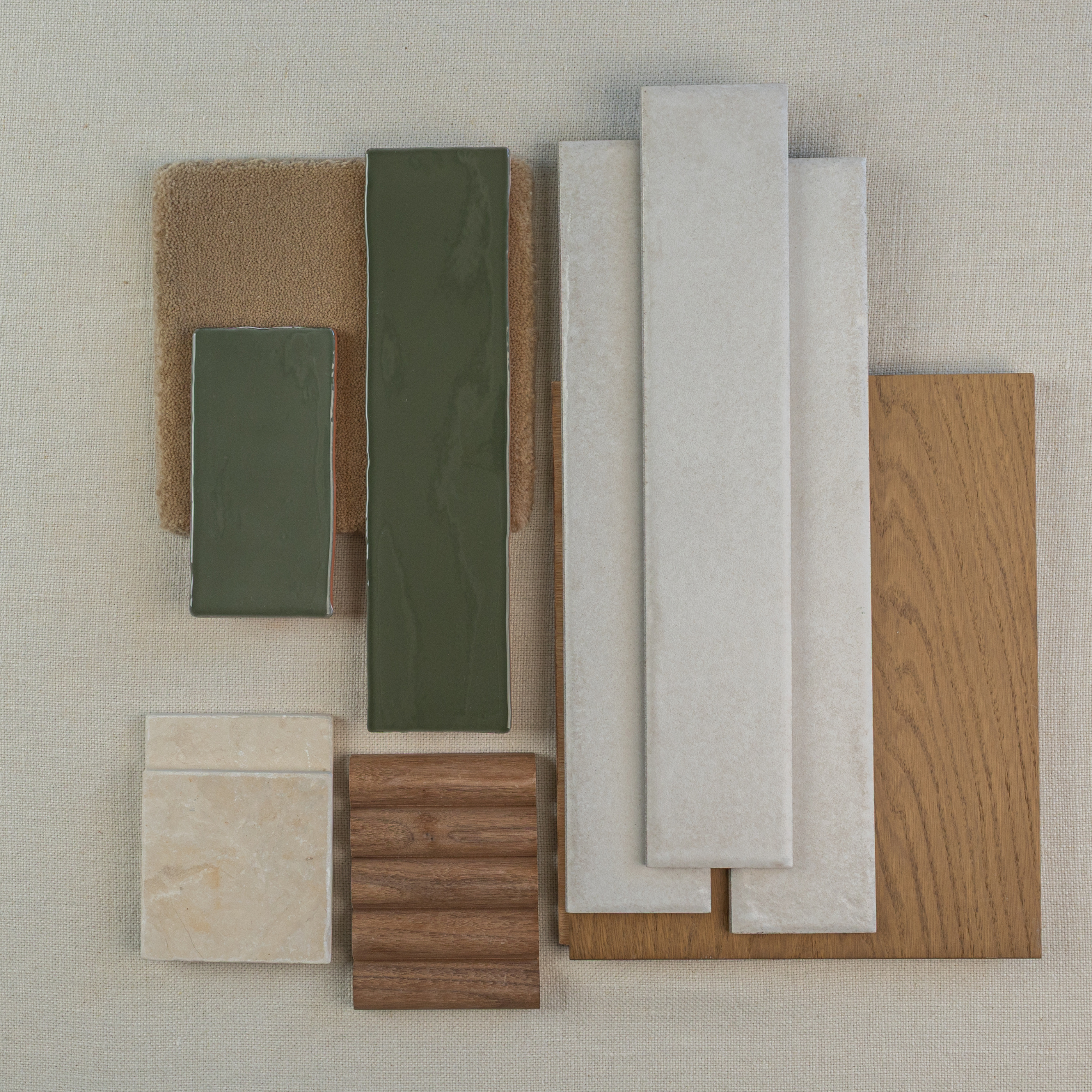 Arrangement of green ceramic tiles, beige porcelain tiles, oak wood sample, and brown textured materials on fabric background