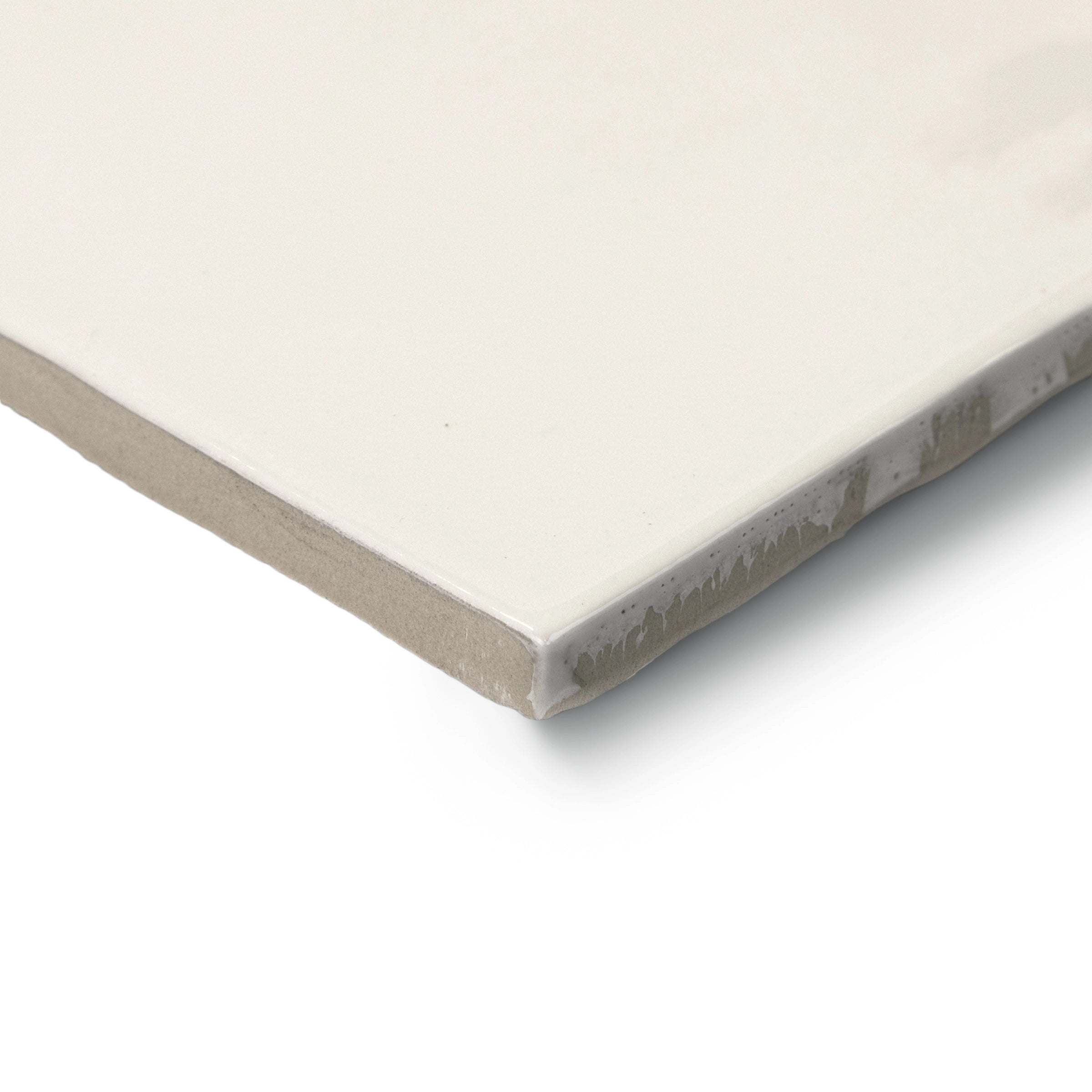 Close-up of a natural ceramic tile corner featuring a smooth, creamy white surface with subtle matte texture and earthy edge tones