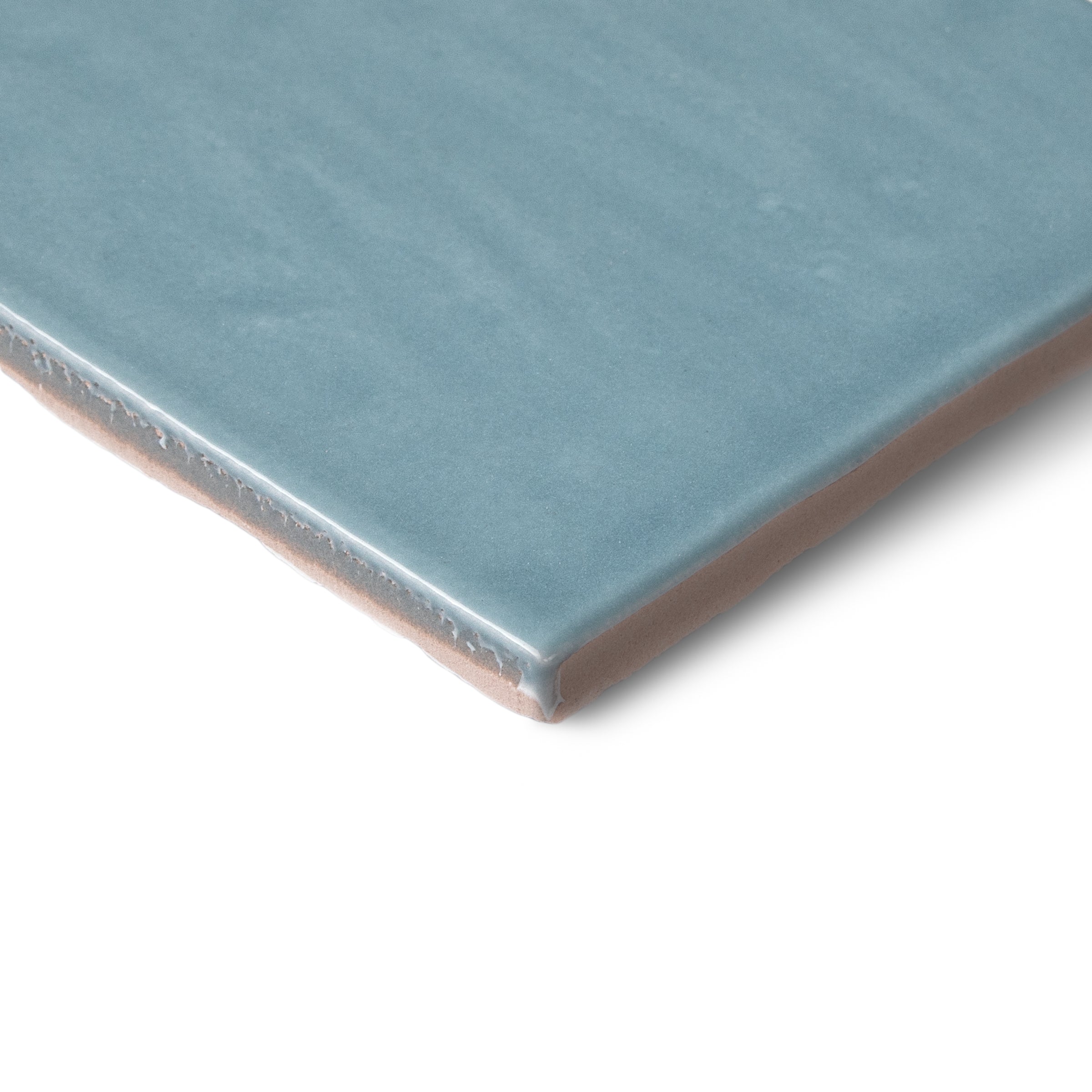 Blue ceramic tile with a glazed surface and exposed edge against a white background