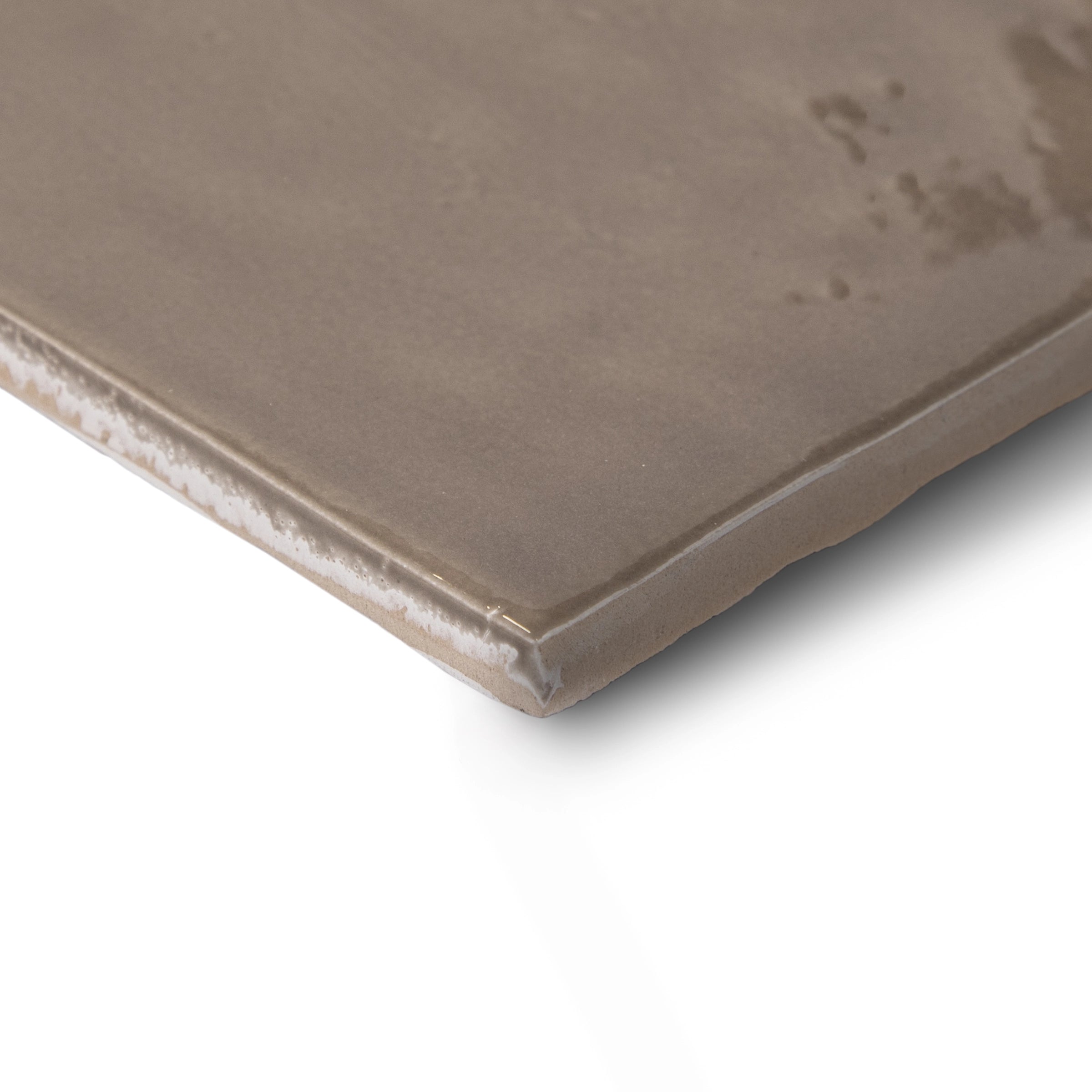 Close-up of a smooth, muted umber ceramic tile with slightly rounded edges and subtle surface texture against white background