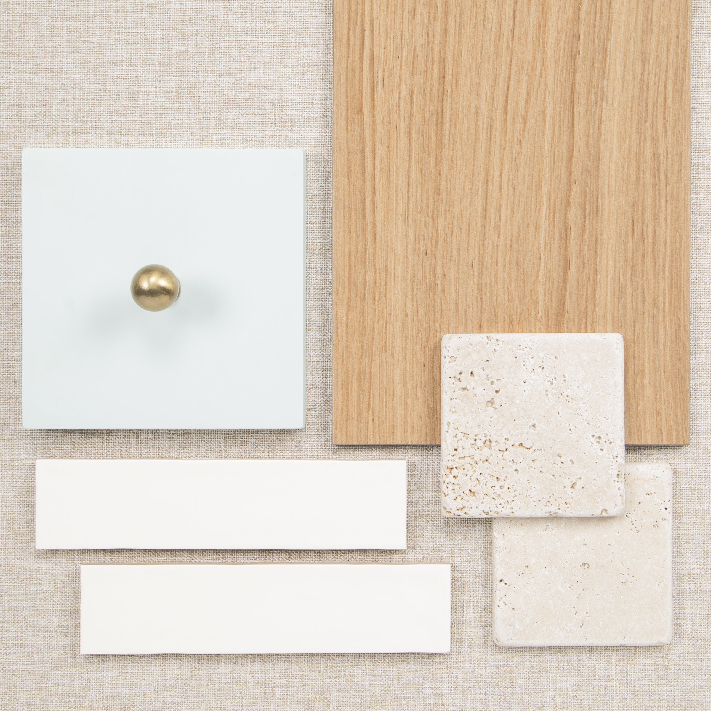 Material samples with light wood white surfaces and textured stone tiles arranged on fabric