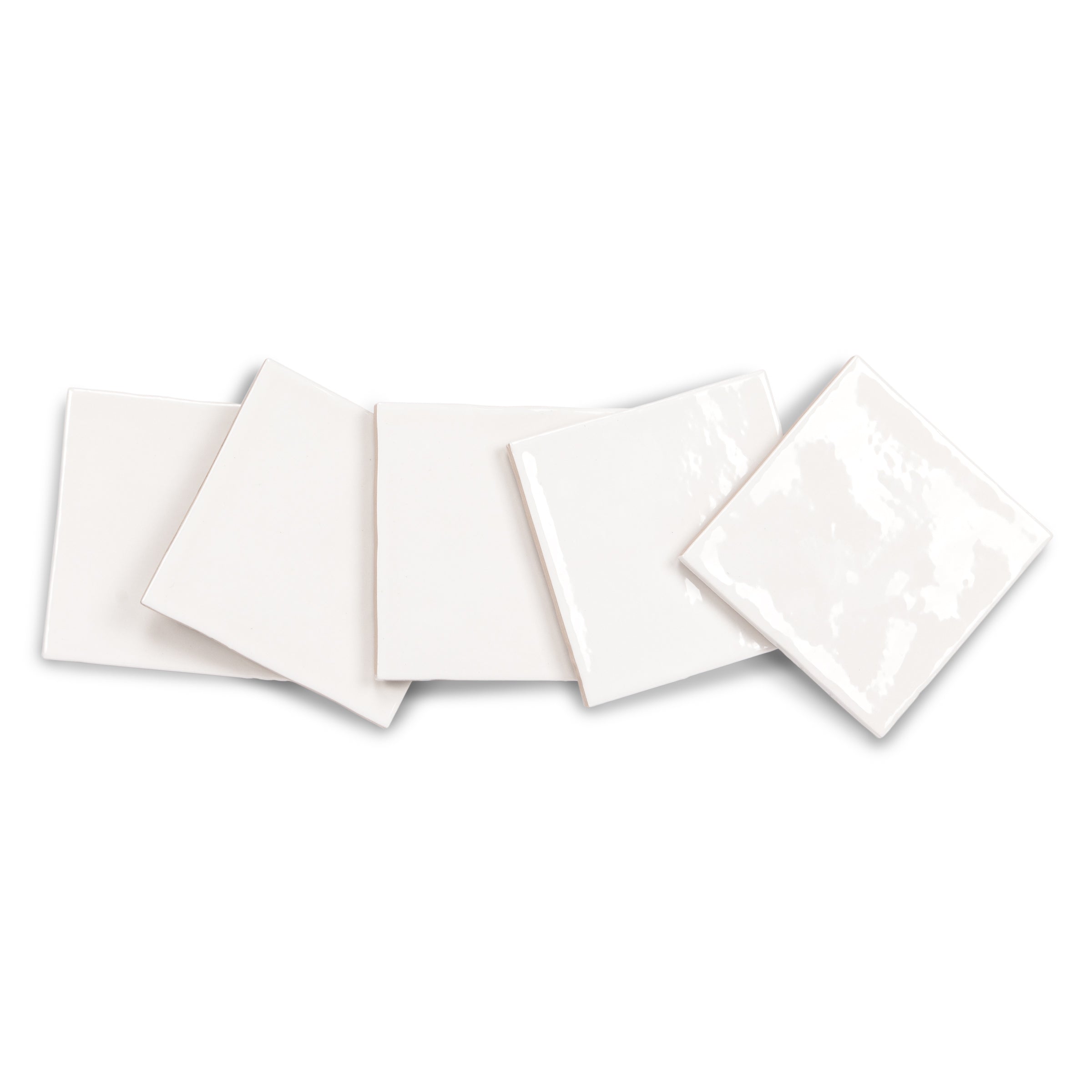 White ceramic tile samples with glossy and subtle textured finishes arranged on a white background