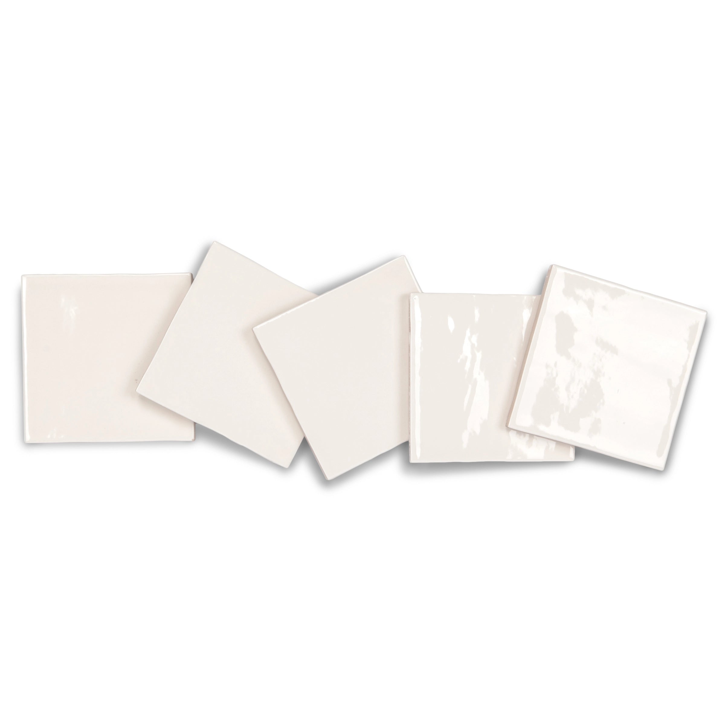 Glossy cream ceramic tiles with smooth surfaces arranged in an overlapping diagonal line on a white background
