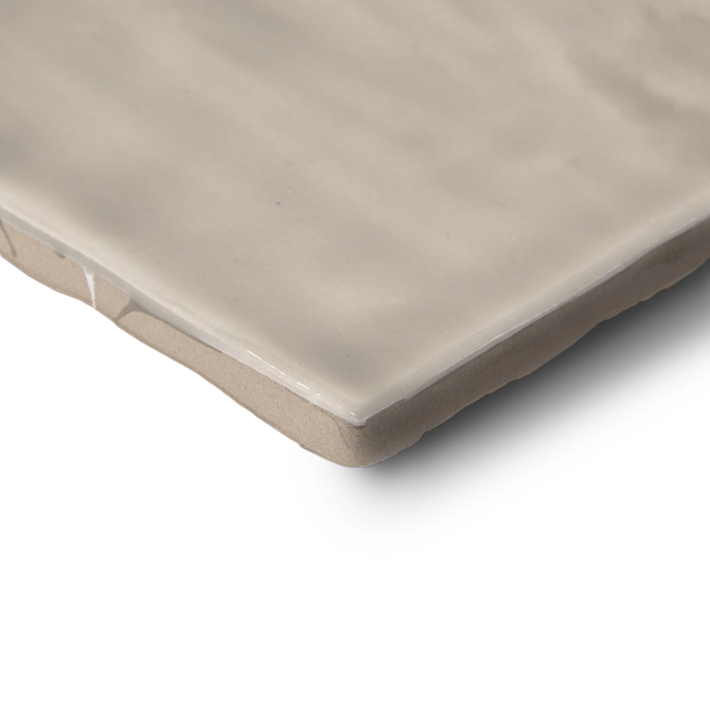 Close-up of a smooth ceramic tile edge in soft cream with a subtle glossy finish and gentle surface ripples