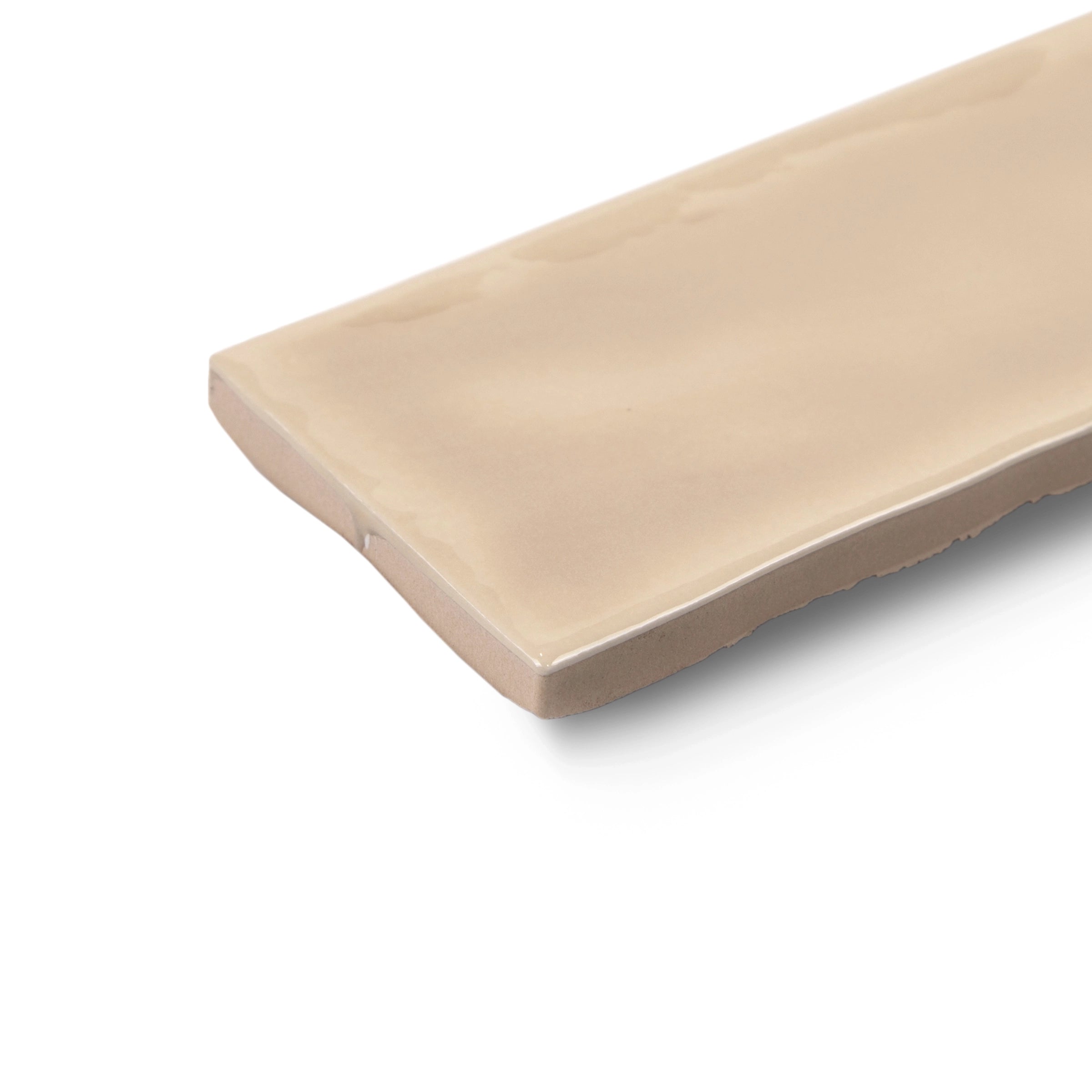 Smooth rectangular ceramic tile in soft beige with a glossy finish and slightly uneven edges on white background