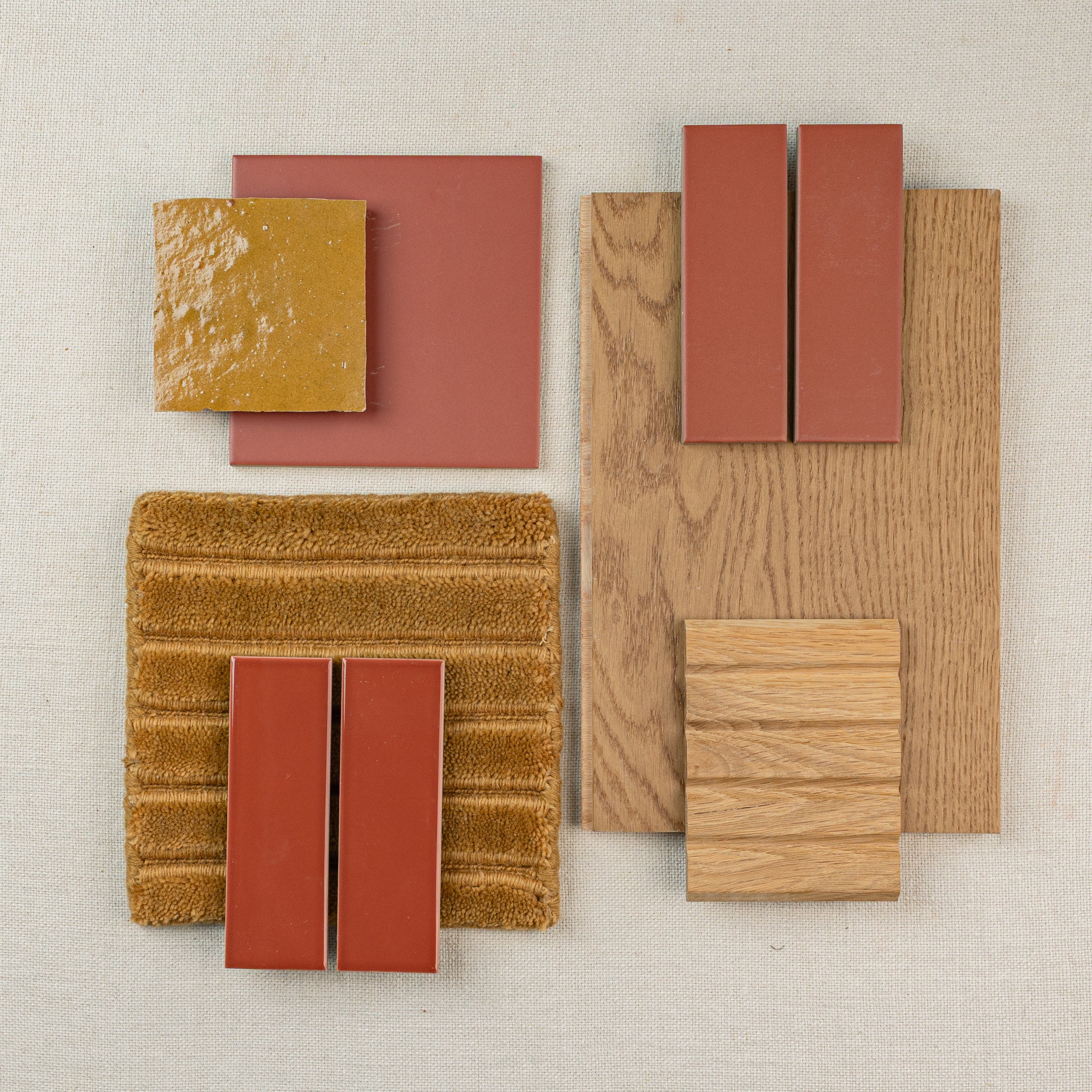 Arrangement of terracotta tiles, oak wood samples, and textured fabric swatches on a neutral background