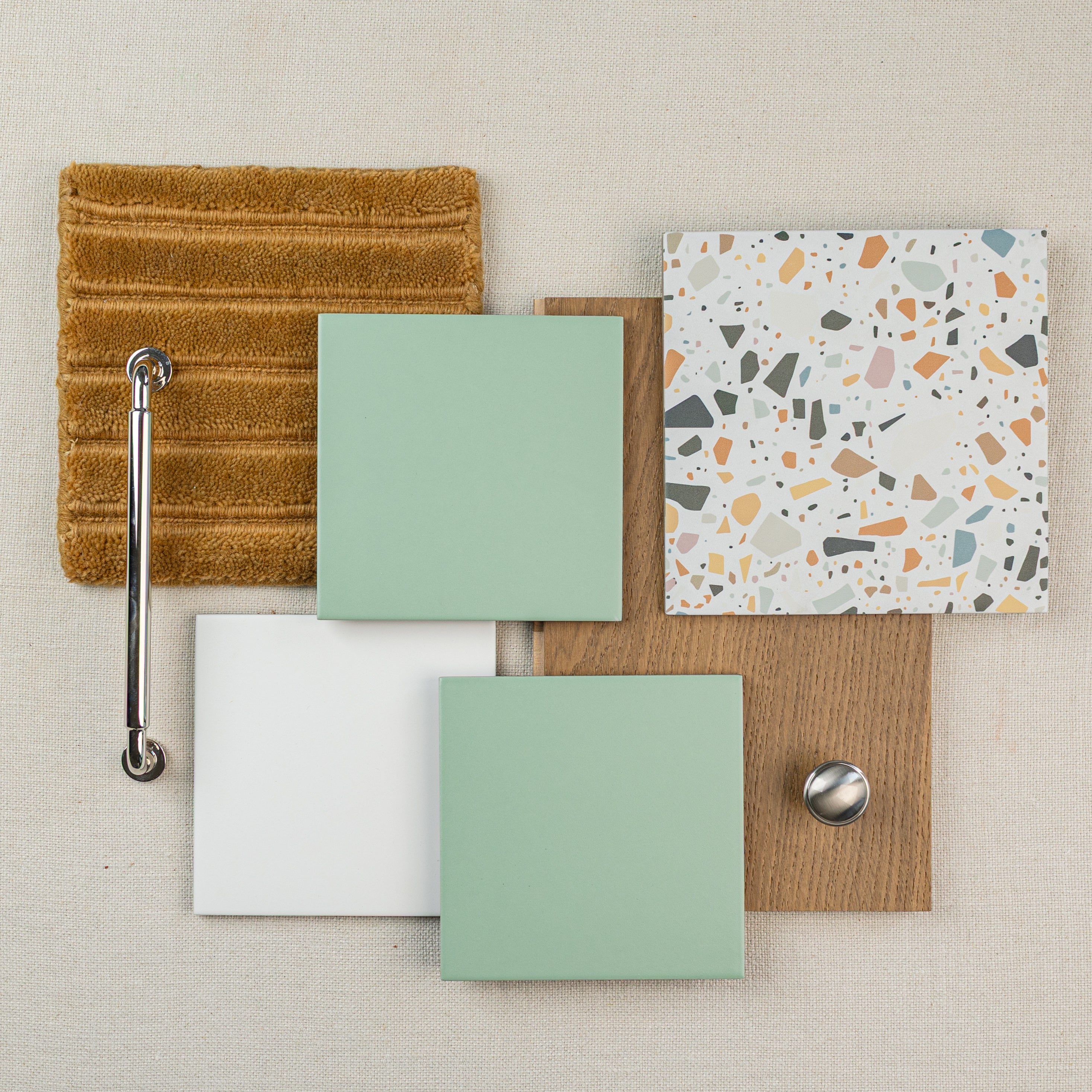 Arrangement of tile samples, wood flooring, a textured brown fabric, and a metal drawer knob on a neutral surface