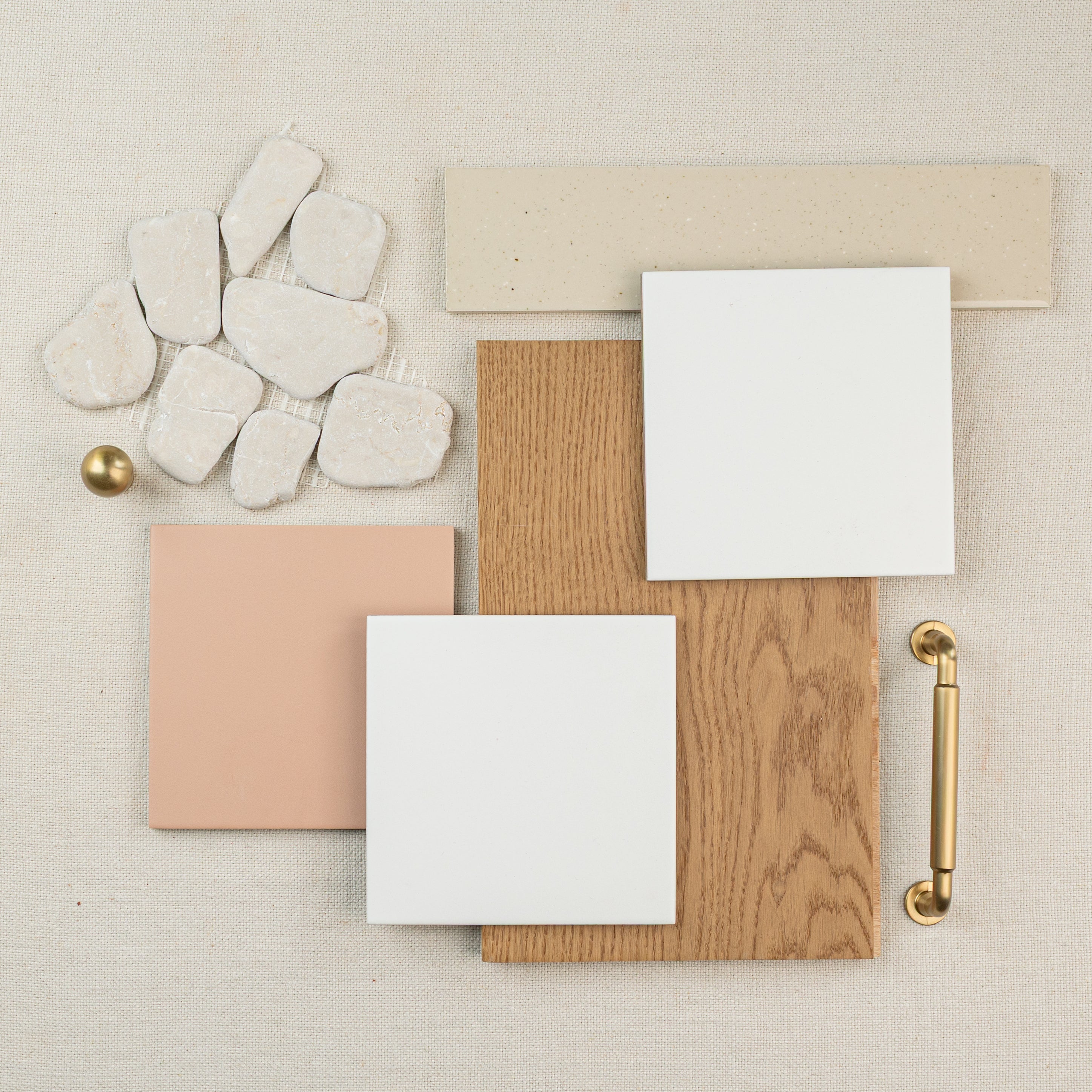 Neutral beige and white tiles arranged with wood and gold hardware on a light fabric background