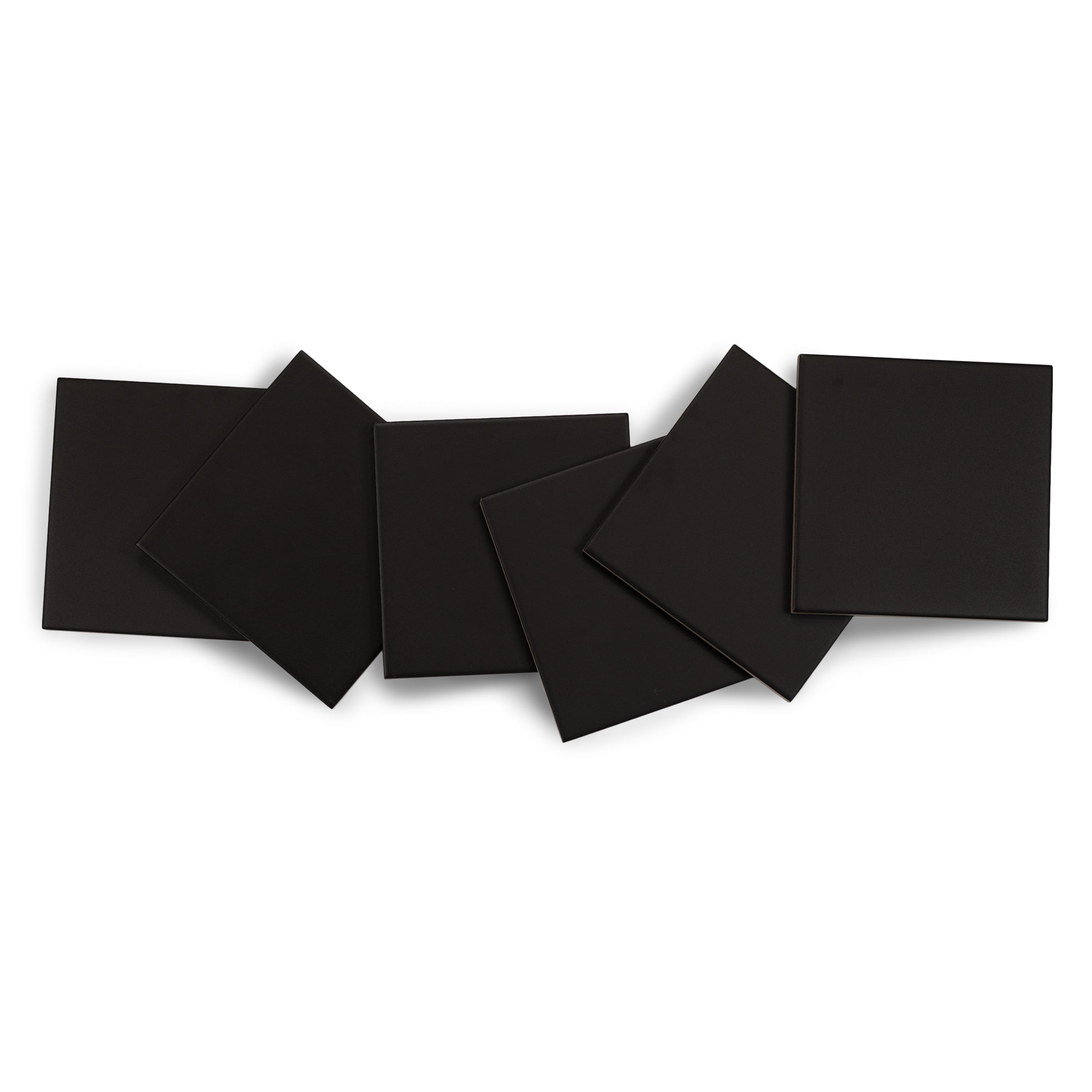 Six matte black square ceramic tiles arranged in a scattered, overlapping layout on a white background