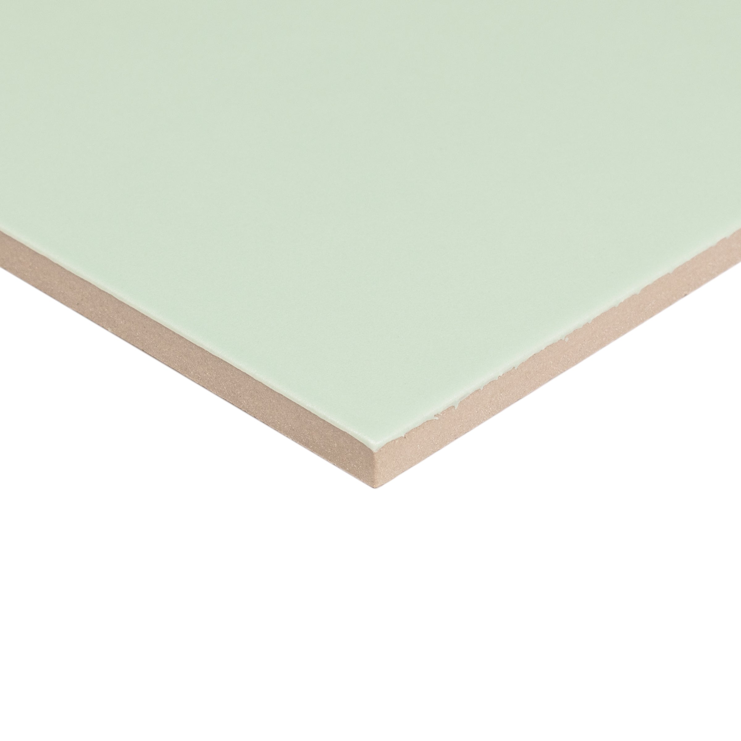 Close-up of a pale green ceramic tile with smooth surface and beige backing edge visible