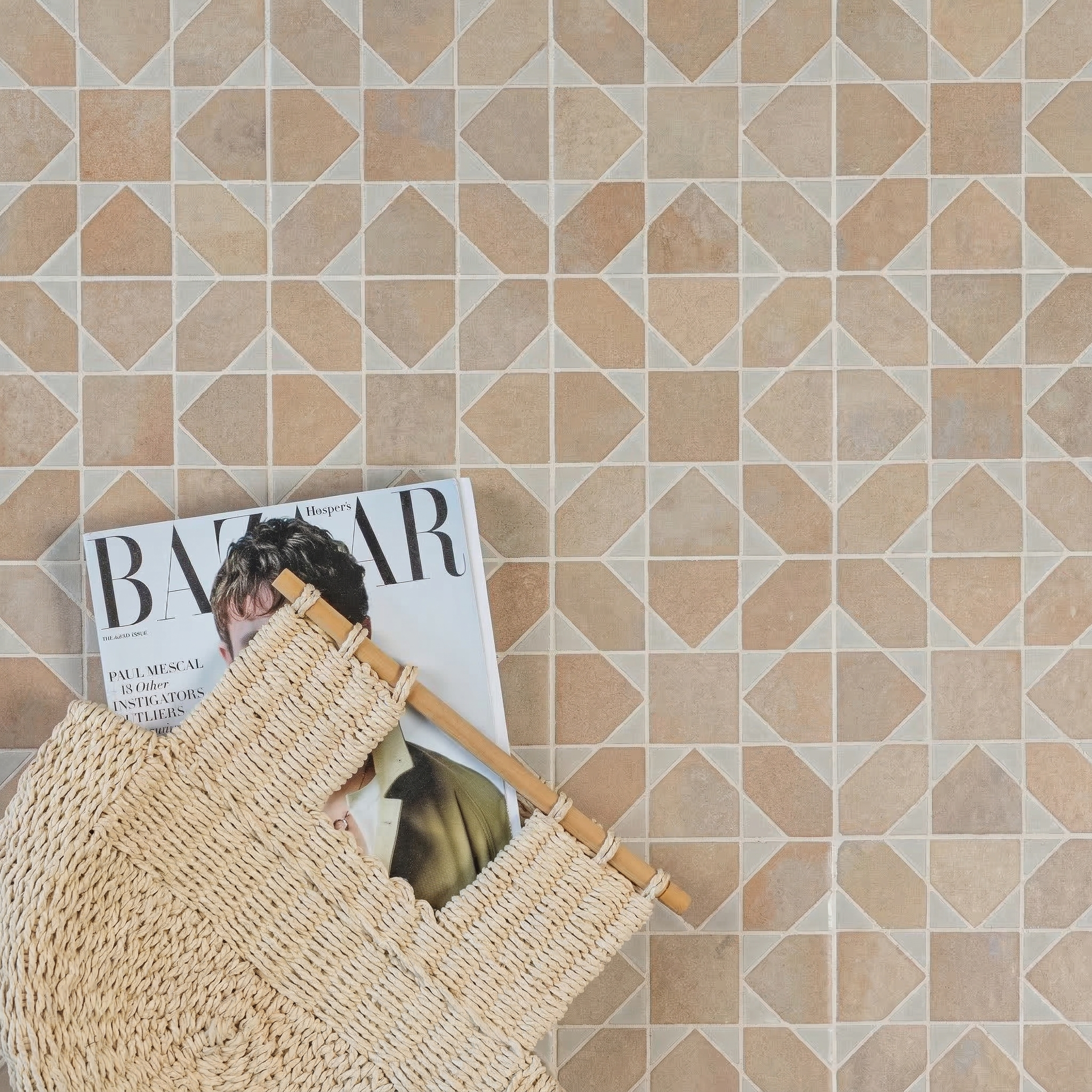 Geometric patterned ceramic tiles in warm beige tones with a woven bag and fashion magazine resting on them