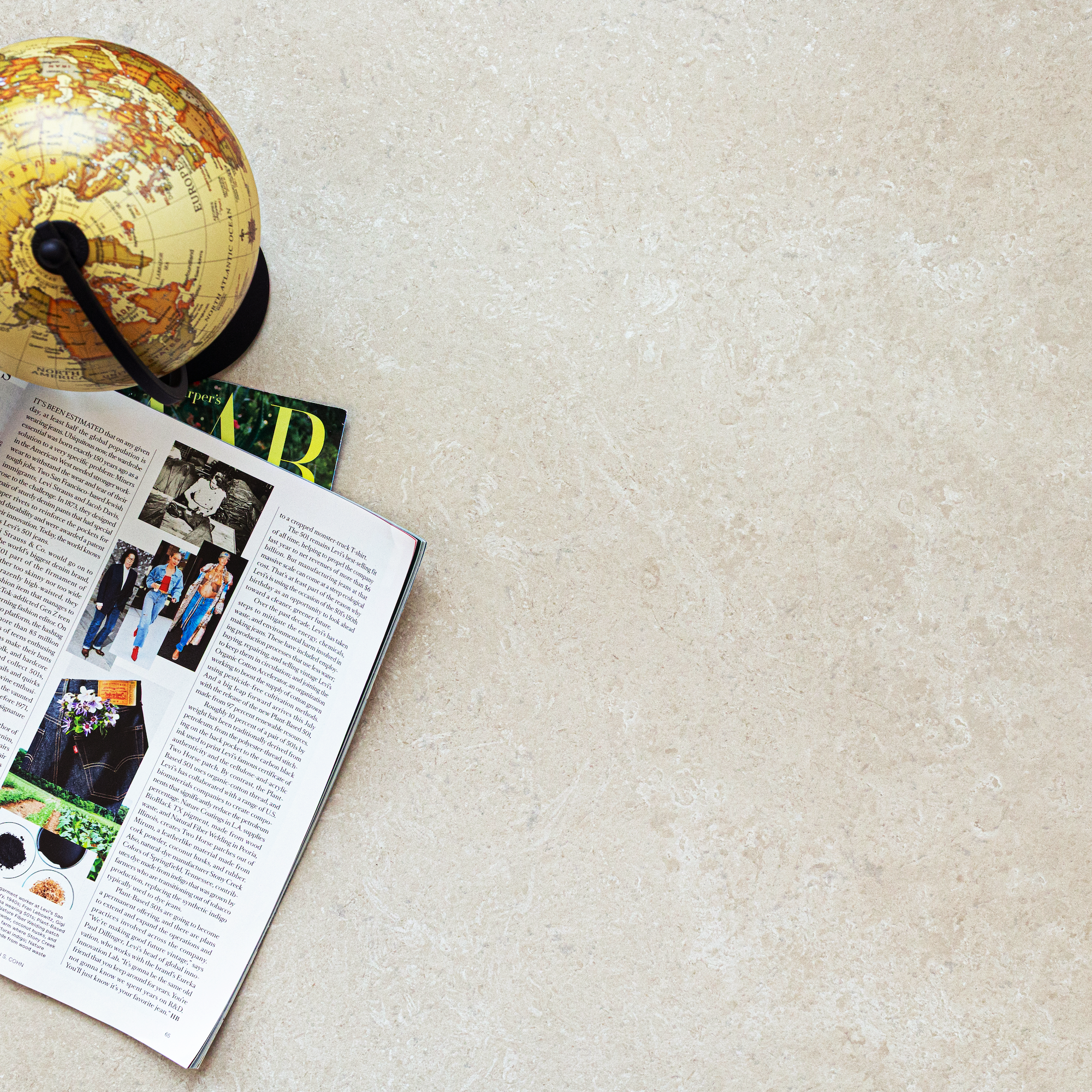 Cream limestone surface with natural veining texture beside an open magazine and a small vintage globe on top