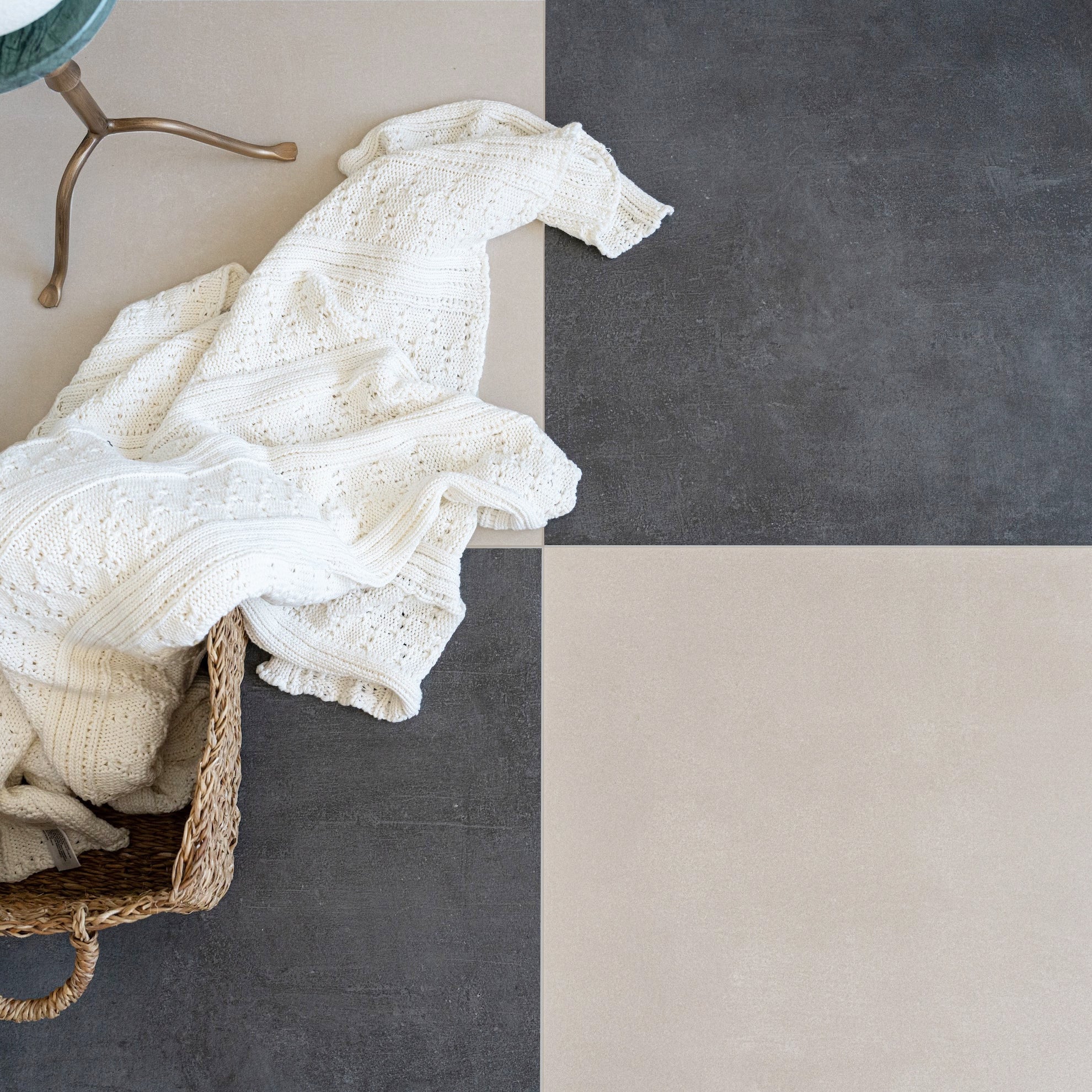 White knitted blanket in a basket beside neutral gray and beige square tiles