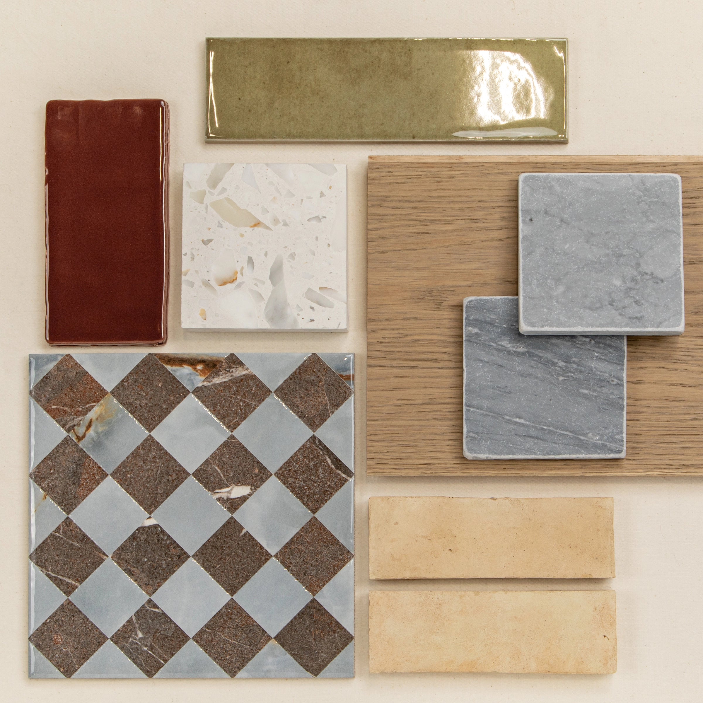 Assortment of ceramic and porcelain tiles, wood samples, and stone-effect tiles arranged on a light surface