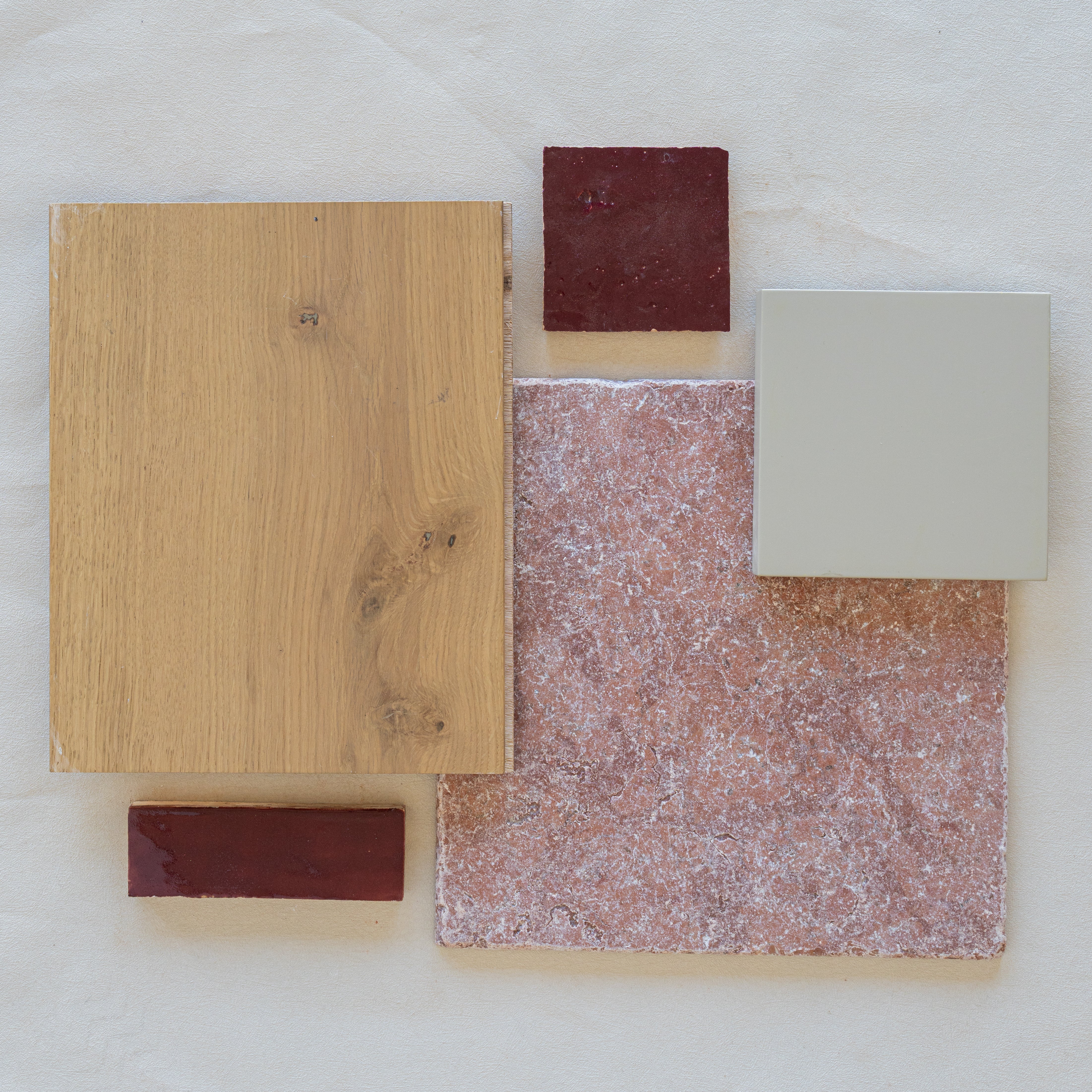 Flat lay of natural oak wood plank with red ceramic tiles and textured pink and beige porcelain tiles on pale background