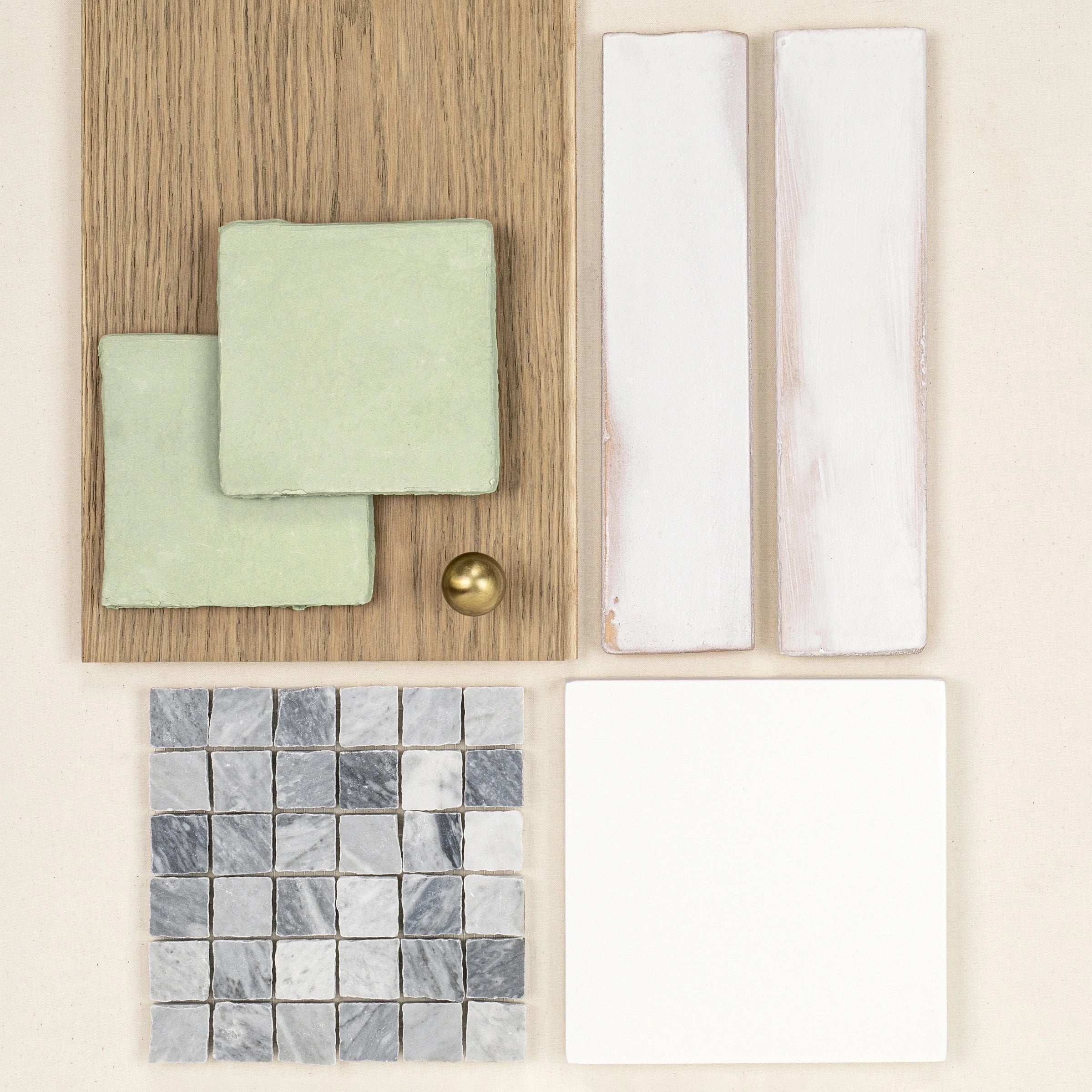 Arrangement of green ceramic tiles, white rectangular tiles, marble mosaic squares, and natural oak wood sample on pale background